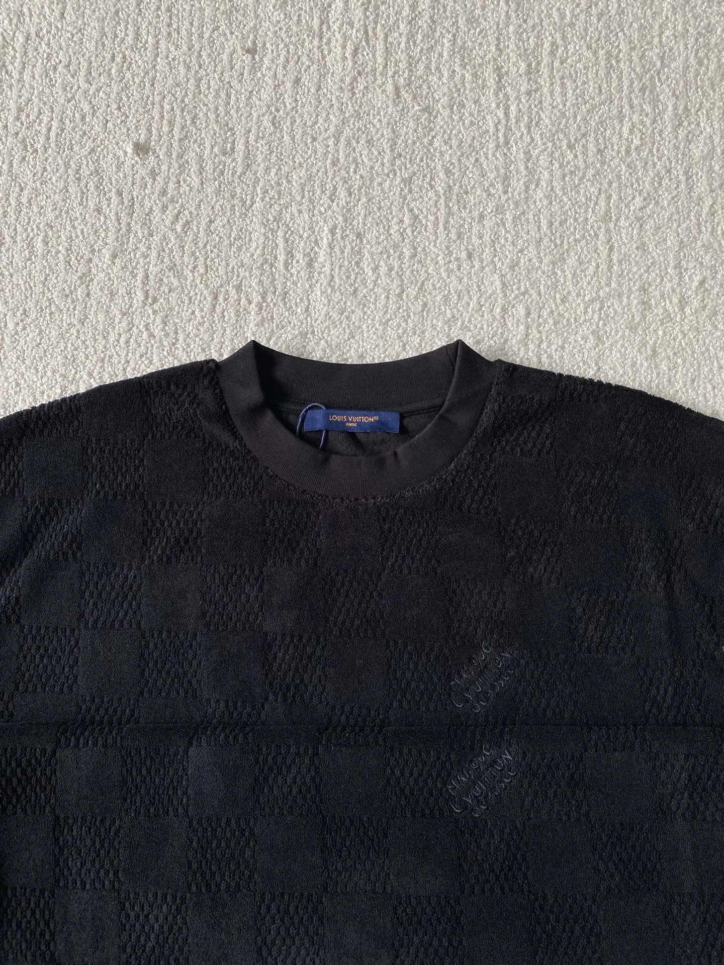 LV towel plaid round neck short sleeves ⚠️Original purchase, 650, standard fit, Damier terry cloth, embroidered Marque L.Uuitton deposee logo on the chest, ribbed collar, floral stitching, full set of accessories with #Damier terry cloth Towel jacquard fabric terry cloth is a fabric that looks like a towel. It has the advantages of high water absorption, good warmth retention, soft hand feel, stiff fabric, and not easy to deform, so it is called terry cloth.  During the weaving process of the full-width embossed pattern, computer digital programming is used to make the plate. The jacquard part has a concave and convex feel, the fabric has a soft and waxy feel, and the fabric details are delicate. The thermal conductivity of towel fabric is low, and because the cotton fiber itself is porous and elastic, a large amount of air can accumulate between the fibers, so the towel fabric has good moisture retention.  #Chest Marque L Uuitton deposee embroidery The chest is embellished with simple letter patterns, and the letter size spacing effect is consistent. Using linen embroidery thread combined with encrypted processing, the embroidery body has a subtle matte visual texture; the embroidery effect is three-dimensional and full. The smaller the embroidery, the more sophisticated and demanding it is. The embroidery thread is made of imported material, which is more flexible and glossy than ordinary embroidery thread; the stitches are clear and smooth, and have a three-dimensional texture effect.  #Positioning Pattern Cutting and Sewing The whole piece positioning pattern sewing process is a fine and complex technology. During the cutting process, it is necessary to ensure that the pattern or texture of each piece can perfectly match other pieces. Through floral tailoring, the checkerboard pattern of ready-made garments appears neatly arranged.  #straight round neck version. Cut and sewed in floral position, standard H hanging version, with shoulder-length design. The vertical version emphasizes that the width of the shoulders, waist, and hem are basically the same, and it is simple and loose. The short sleeves are tailored to fit the body of the wearer. At the same time, the neckline, cuffs and hem of the short sleeves are all designed with double lines.