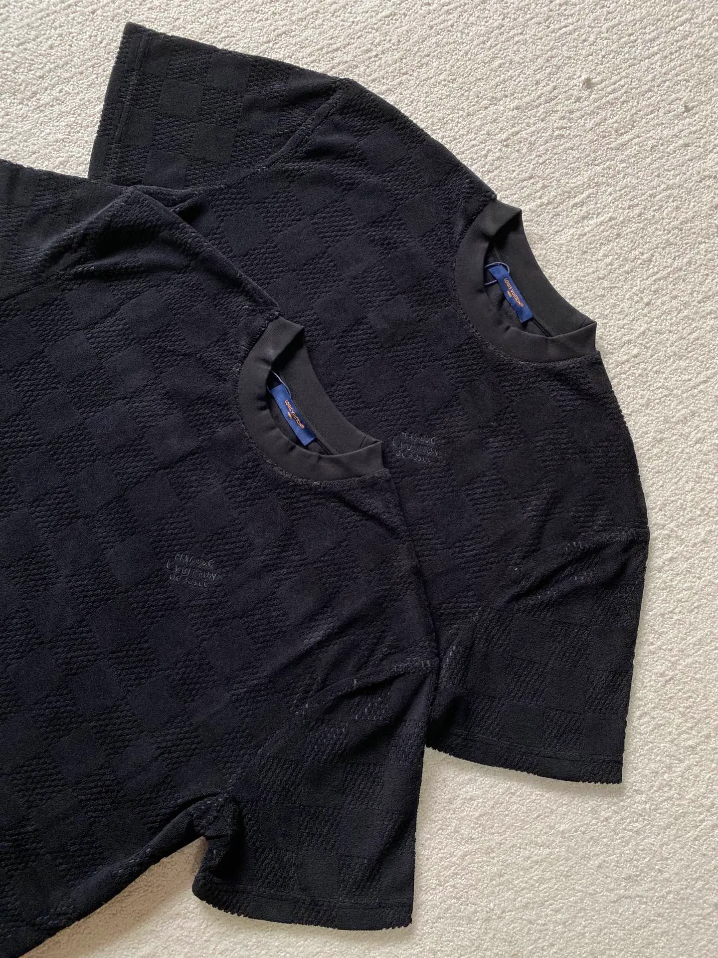 LV towel plaid round neck short sleeves ⚠️Original purchase, 650, standard fit, Damier terry cloth, embroidered Marque L.Uuitton deposee logo on the chest, ribbed collar, floral stitching, full set of accessories with #Damier terry cloth Towel jacquard fabric terry cloth is a fabric that looks like a towel. It has the advantages of high water absorption, good warmth retention, soft hand feel, stiff fabric, and not easy to deform, so it is called terry cloth.  During the weaving process of the full-width embossed pattern, computer digital programming is used to make the plate. The jacquard part has a concave and convex feel, the fabric has a soft and waxy feel, and the fabric details are delicate. The thermal conductivity of towel fabric is low, and because the cotton fiber itself is porous and elastic, a large amount of air can accumulate between the fibers, so the towel fabric has good moisture retention.  #Chest Marque L Uuitton deposee embroidery The chest is embellished with simple letter patterns, and the letter size spacing effect is consistent. Using linen embroidery thread combined with encrypted processing, the embroidery body has a subtle matte visual texture; the embroidery effect is three-dimensional and full. The smaller the embroidery, the more sophisticated and demanding it is. The embroidery thread is made of imported material, which is more flexible and glossy than ordinary embroidery thread; the stitches are clear and smooth, and have a three-dimensional texture effect.  #Positioning Pattern Cutting and Sewing The whole piece positioning pattern sewing process is a fine and complex technology. During the cutting process, it is necessary to ensure that the pattern or texture of each piece can perfectly match other pieces. Through floral tailoring, the checkerboard pattern of ready-made garments appears neatly arranged.  #straight round neck version. Cut and sewed in floral position, standard H hanging version, with shoulder-length design. The vertical version emphasizes that the width of the shoulders, waist, and hem are basically the same, and it is simple and loose. The short sleeves are tailored to fit the body of the wearer. At the same time, the neckline, cuffs and hem of the short sleeves are all designed with double lines.