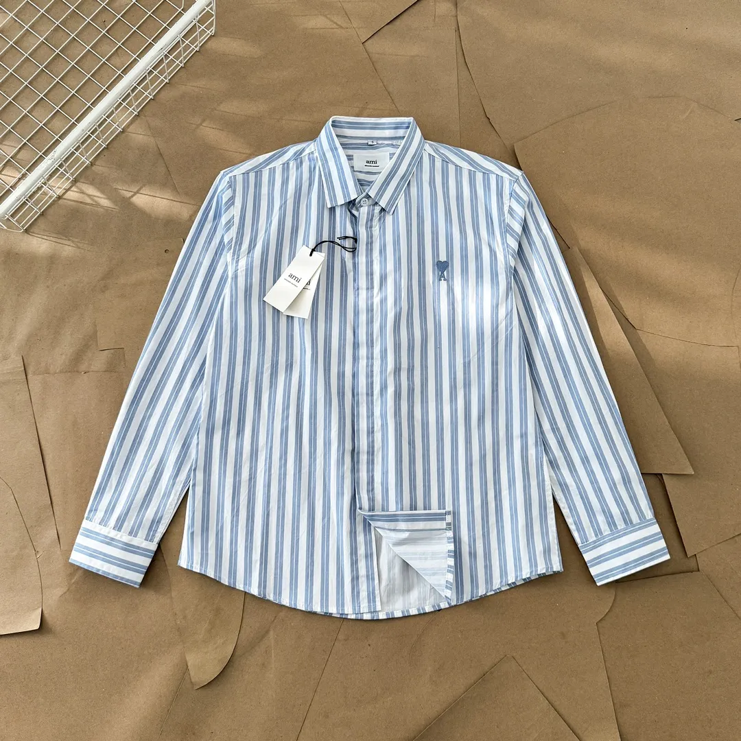 Ami Paris Oxford cotton button-down corner collar casual shirt-blue heart thick striped long-sleeved shirt-same style for men and women. Blue small love letter embroidery decoration fashionable and versatile long-sleeved shirt! On sale simultaneously at counters!  A well-known French affordable luxury fashion brand. The brand's classic elements are embellishments sought after by major celebrities. Its basic simple design and fashionable style make it a must-have couple's shirt for men and women!  Made of custom-woven 100% Oxford cloth pure cotton, it feels soft and delicate, has excellent moisture absorption and perspiration performance, and is very comfortable and skin-friendly when worn next to the skin! The chest of the shirt is decorated with the classic love letter A logo embroidery. The top-notch embroidery technology is tight, full and full of details, and is cleverly embellished with bright red. It carries all the eye-catching points. It follows the consistent minimalist French attitude. The fabric is soft and comfortable, suitable for any versatile casual shirt couple!  Color: Blue Stripe Size: S-XL S: Bust 106 Shoulder Width 47 Clothing Length 71 Sleeve Length 60 M: Bust 110 Shoulder Width 48 Clothing Length 73 Sleeve Length 61 L: Bust 114 Shoulder Width 49 Clothing Length 75 Sleeve Length 62