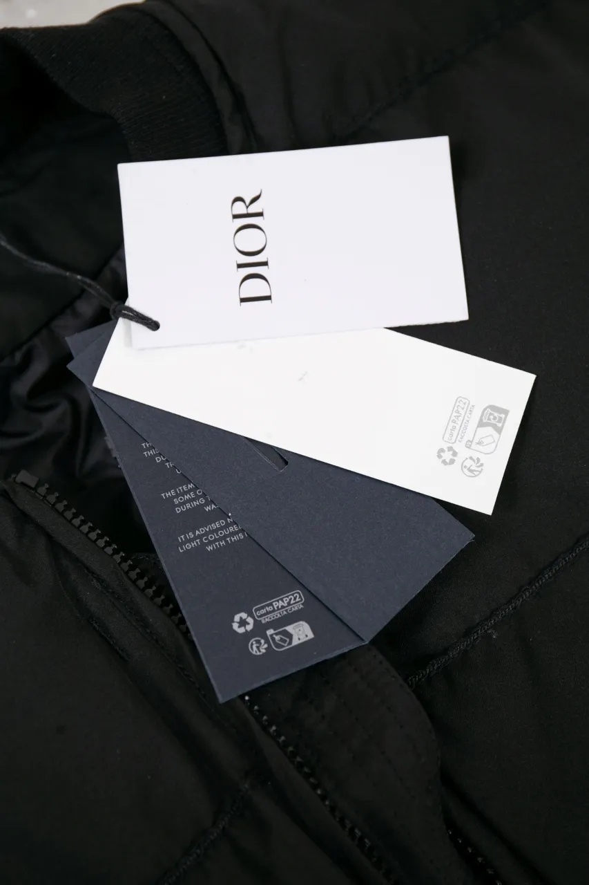 DIOR AND LEWIS HAMILTON JACKET Black technical fabric with removable sleeves This jacket is from the DIOR AND LEWIS HAMILTON limited series. Crafted from black technical fabric and embellished with DIOR AND LEWIS HAMILTON embroidery, the graphic design highlights the iconic Dior signature. With detachable sleeves, it can be worn in two different ways. It can be paired with jeans to create a low-key sporty look. DIOR AND LEWIS HAMILTON Embroidery and zip Knitted collar Detachable sleeves Front and internal flapless pockets Body: 100% nylon, Lining: 100% nylon