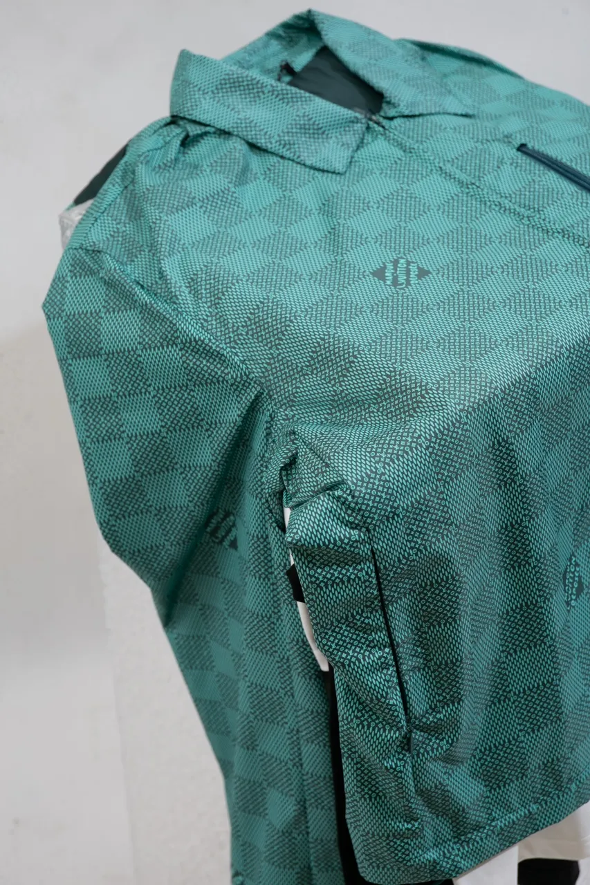 LV Printed Nylon Hooded Windproof Jacket This technical hooded windbreaker combines functional details with the season's nautical theme, sublimating the trend with an all-over Damier Monogram pattern, incorporating micro Monogram details and the Marque L.Vuitton Déposée logo. Fresh colors complete the casual design.  SMLXL