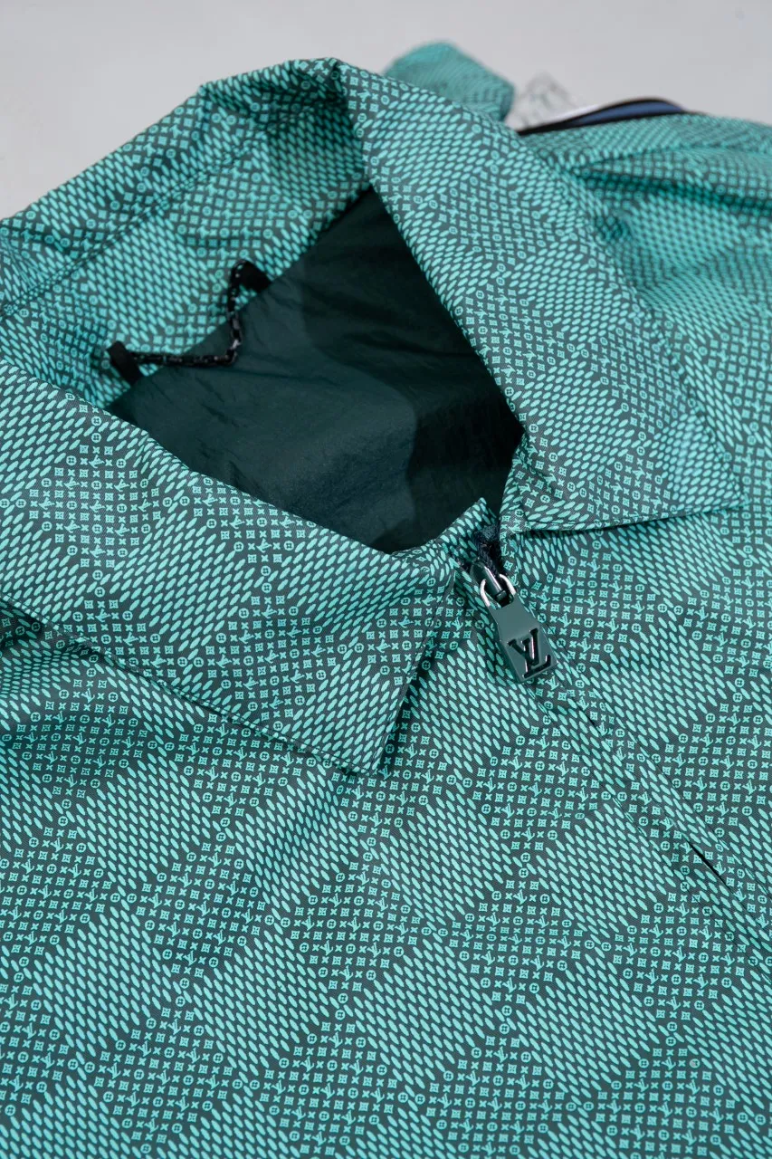 LV Printed Nylon Hooded Windproof Jacket This technical hooded windbreaker combines functional details with the season's nautical theme, sublimating the trend with an all-over Damier Monogram pattern, incorporating micro Monogram details and the Marque L.Vuitton Déposée logo. Fresh colors complete the casual design.  SMLXL