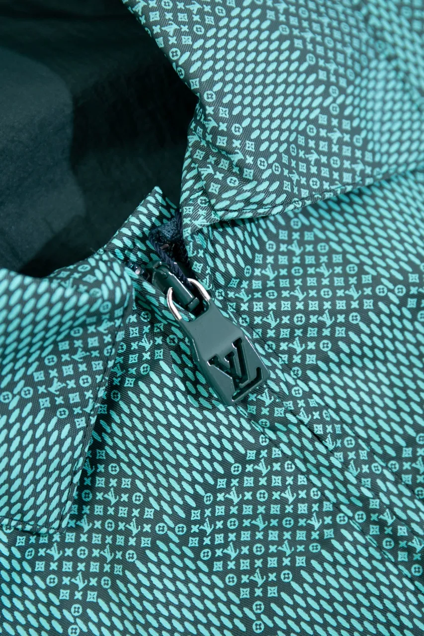 LV Printed Nylon Hooded Windproof Jacket This technical hooded windbreaker combines functional details with the season's nautical theme, sublimating the trend with an all-over Damier Monogram pattern, incorporating micro Monogram details and the Marque L.Vuitton Déposée logo. Fresh colors complete the casual design.  SMLXL