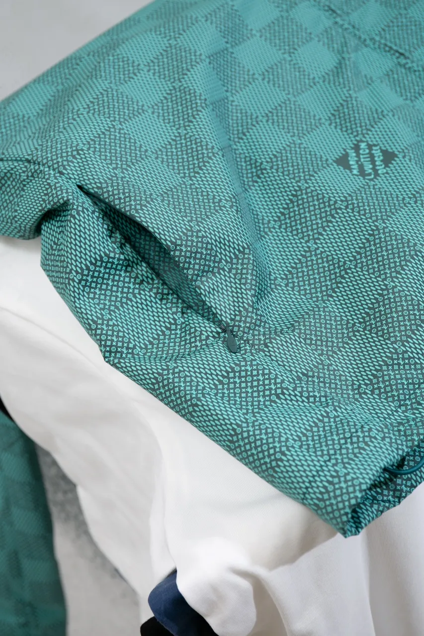 LV Printed Nylon Hooded Windproof Jacket This technical hooded windbreaker combines functional details with the season's nautical theme, sublimating the trend with an all-over Damier Monogram pattern, incorporating micro Monogram details and the Marque L.Vuitton Déposée logo. Fresh colors complete the casual design.  SMLXL