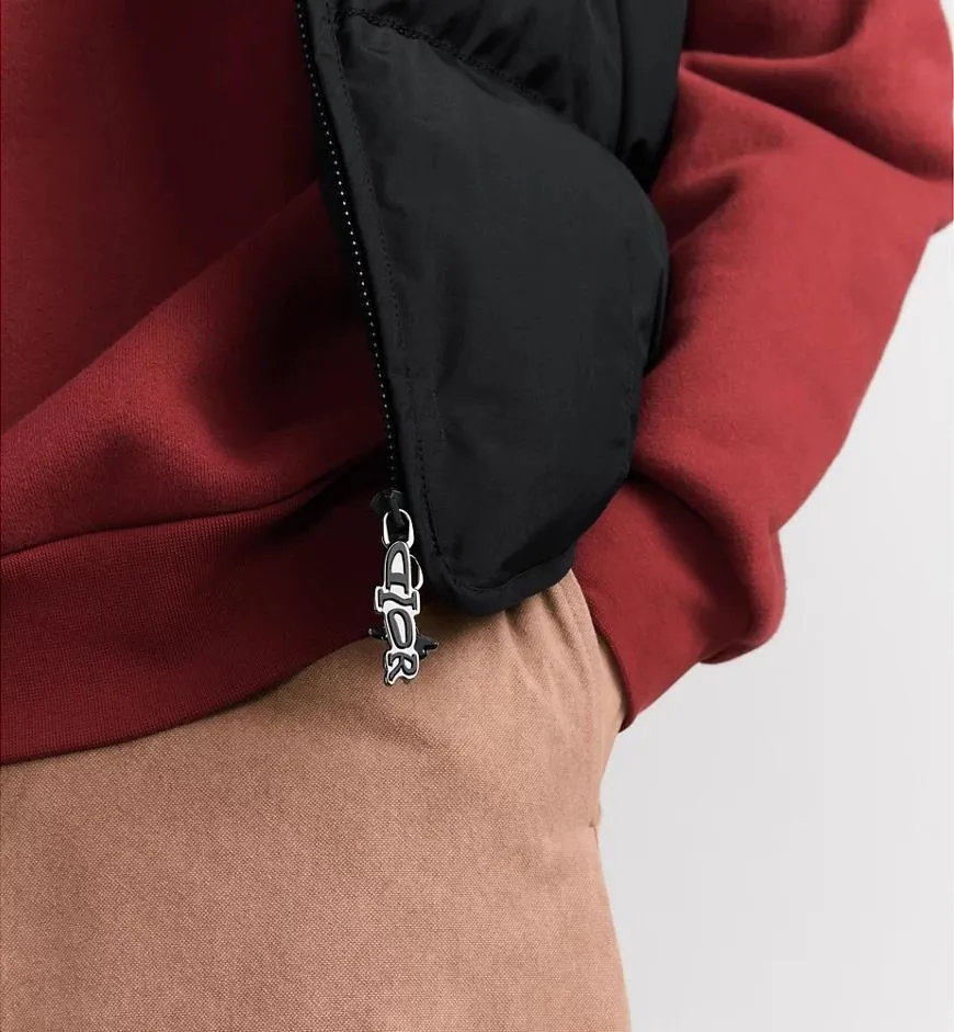 Official website DIOR AND LEWIS HAMILTON Jacket Black technical fabric with removable sleeves This jacket is from the DIOR AND LEWIS HAMILTON limited series. Crafted from black technical fabric and embellished with DIOR AND LEWIS HAMILTON embroidery, the graphic design highlights the iconic Dior signature. With detachable sleeves, it can be worn in two different ways. It can be paired with jeans to create a low-key sporty look. DIOR AND LEWIS HAMILTON Embroidery and zip Knitted collar Detachable sleeves Front and internal flapless pockets Body: 100% nylon, Lining: 100% nylon