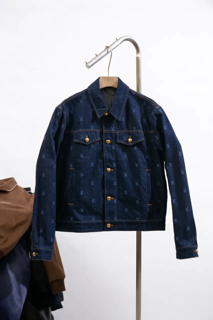 LV Embroidered Denim Tunic Jacket This belted jacket is crafted from washed denim in a classic trucker jacket silhouette, with yarn embroidery depicting the all-over LV Blason pattern and contrasting topstitching and button details. Metallic LV accents and a Damier nubuck label perch on the back make it perfect for the season with the matching trousers.  Regular fit All-over LV Blason embroidery Rear nubuck label with metallic LV accents Denim buttons at front