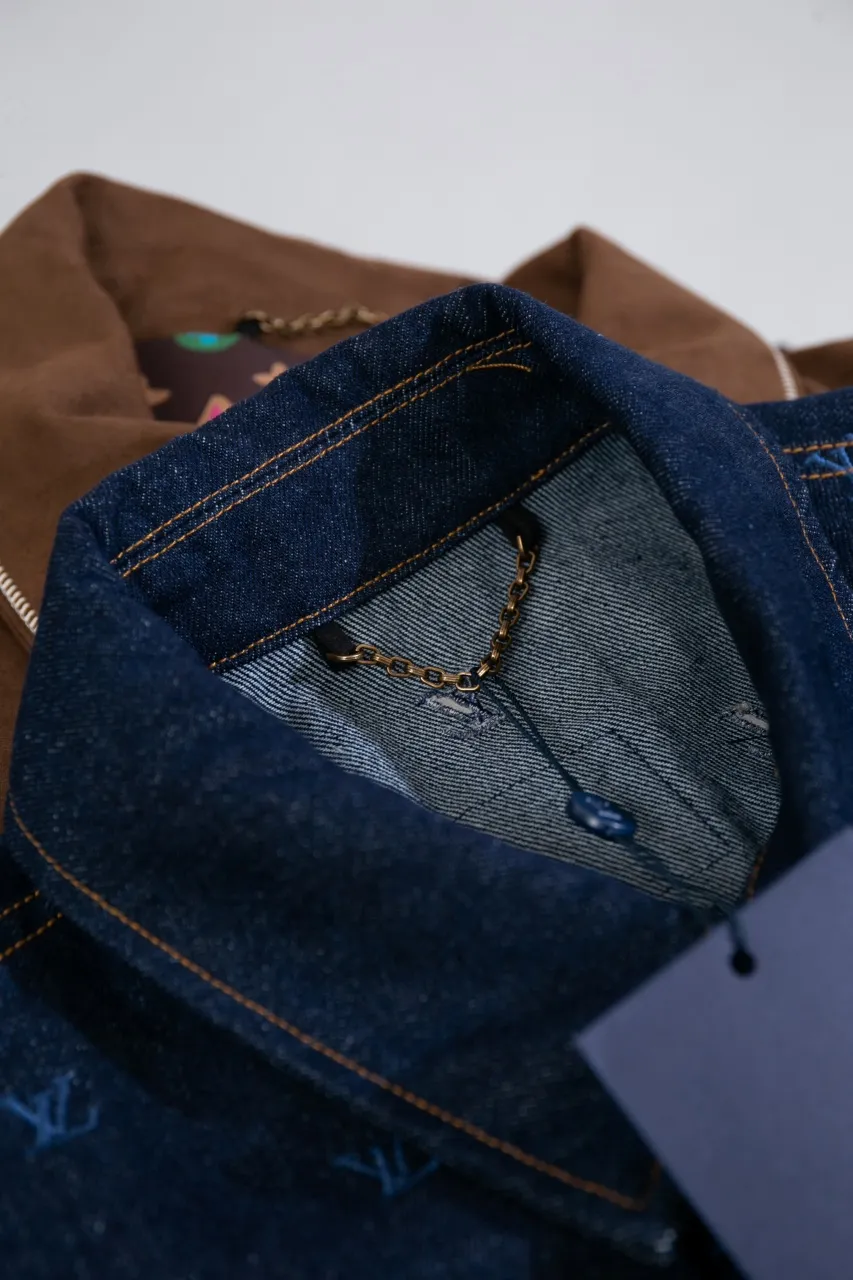 LV Embroidered Denim Tunic Jacket This belted jacket is crafted from washed denim in a classic trucker jacket silhouette, with yarn embroidery depicting the all-over LV Blason pattern and contrasting topstitching and button details. Metallic LV accents and a Damier nubuck label perch on the back make it perfect for the season with the matching trousers.  Regular fit All-over LV Blason embroidery Rear nubuck label with metallic LV accents Denim buttons at front