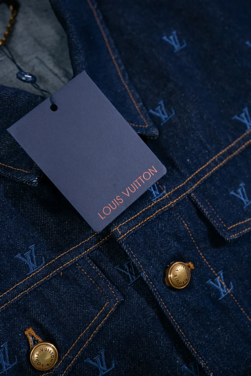 LV Embroidered Denim Tunic Jacket This belted jacket is crafted from washed denim in a classic trucker jacket silhouette, with yarn embroidery depicting the all-over LV Blason pattern and contrasting topstitching and button details. Metallic LV accents and a Damier nubuck label perch on the back make it perfect for the season with the matching trousers.  Regular fit All-over LV Blason embroidery Rear nubuck label with metallic LV accents Denim buttons at front
