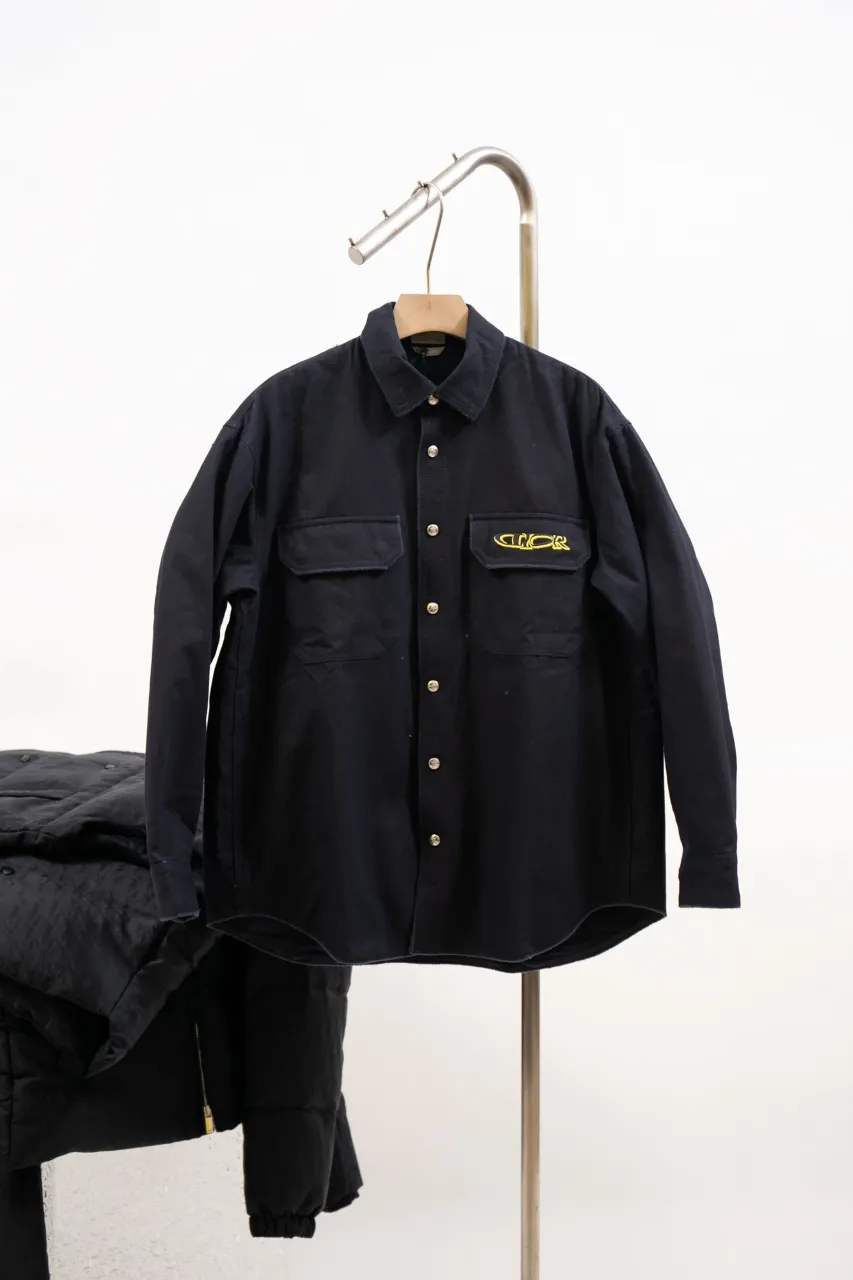 DIOR AND LEWIS HAMILTON Navy blue cotton denim overshirt This overshirt is from the DIOR AND LEWIS HAMILTON limited collection. Crafted from navy blue cotton denim, it features contrasting DIOR AND LEWIS HAMILTON embroidery on the chest and back, a graphic design highlighting Dior's iconic signature. Wear it with the matching jeans for a comfortable, oversized fit. Contrasting DIOR AND LEWIS HAMILTON embroidery on chest and back Button closure and cuffs Chest flap pocket 100% cotton