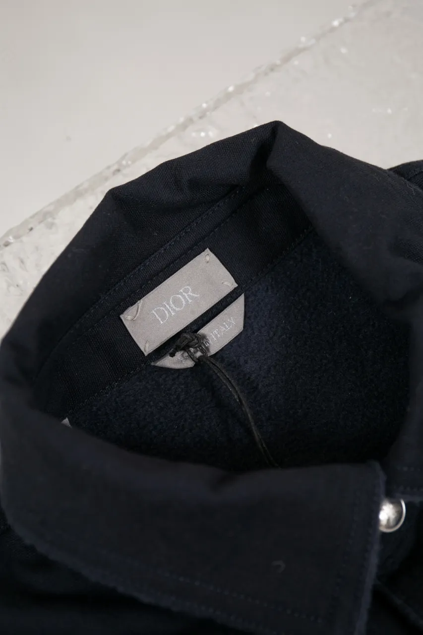 DIOR AND LEWIS HAMILTON Navy blue cotton denim overshirt This overshirt is from the DIOR AND LEWIS HAMILTON limited collection. Crafted from navy blue cotton denim, it features contrasting DIOR AND LEWIS HAMILTON embroidery on the chest and back, a graphic design highlighting Dior's iconic signature. Wear it with the matching jeans for a comfortable, oversized fit. Contrasting DIOR AND LEWIS HAMILTON embroidery on chest and back Button closure and cuffs Chest flap pocket 100% cotton