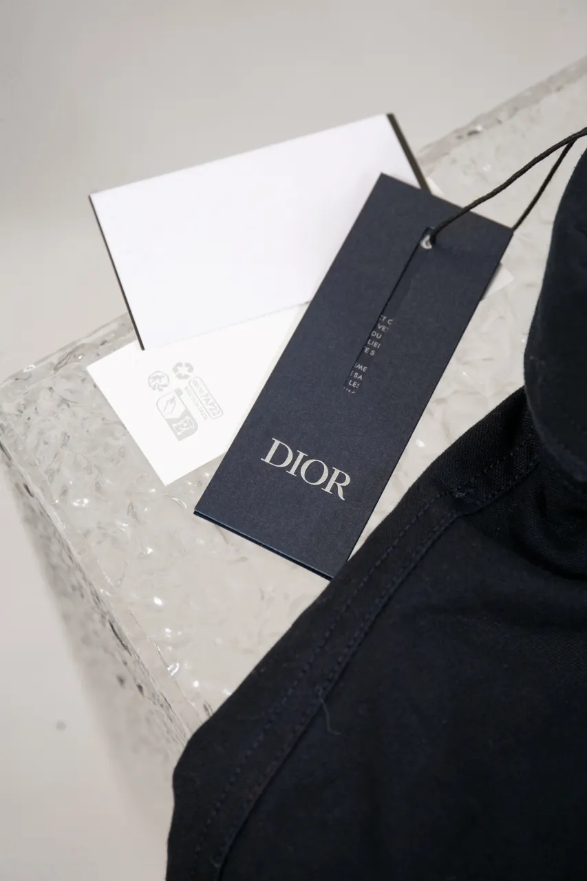 DIOR AND LEWIS HAMILTON Navy blue cotton denim overshirt This overshirt is from the DIOR AND LEWIS HAMILTON limited collection. Crafted from navy blue cotton denim, it features contrasting DIOR AND LEWIS HAMILTON embroidery on the chest and back, a graphic design highlighting Dior's iconic signature. Wear it with the matching jeans for a comfortable, oversized fit. Contrasting DIOR AND LEWIS HAMILTON embroidery on chest and back Button closure and cuffs Chest flap pocket 100% cotton