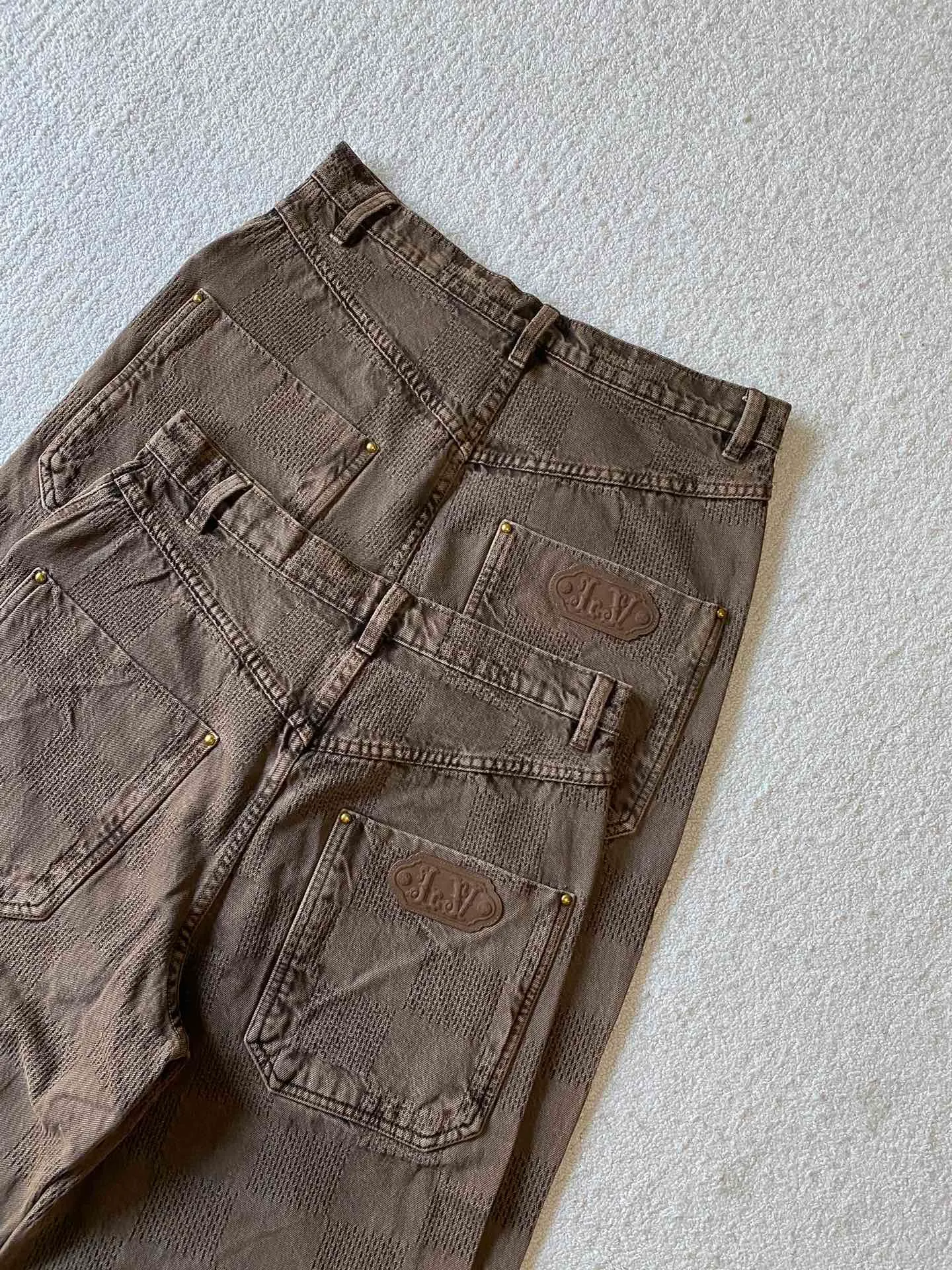 LU brown checkerboard denim straight trousers ⚠️Original purchase, 600, skateboard straight version, Marque L. Uuitton deposee logo integrated into 3D Damier jacquard, back Damier label, sand washed distressed, topstitch sewing, placket distressed hardware closure #Logo integrated into 3D Damier jacquard 3D Damier jacquard denim fabric is an innovative fabric that combines jacquard technology and the characteristics of denim cloth. The classic plaid pattern is combined with 3D jacquard technology to weave three-dimensional patterns on the fabric through a loom.  The fabric presents an exquisite plaid pattern in appearance, and the pattern is made three-dimensional and layered through jacquard technology. At the same time, it retains the original tough, wear-resistant and durable properties of denim, making the clothes more durable.  # Sandwashed, Faded and Distressed Effect Sandwashed, faded and distressed denim fabric is a specially treated denim fabric that exhibits a whitened and distressed effect. This fabric uses a sand-washing process and special dyeing technology to create a natural wear and fading effect on the denim after washing, making it look more vintage and historical.  #skateboard straight jeans version Skateboard jeans are usually designed to be looser to accommodate the large movements and squatting postures during skateboarding. Jeans have a straight shape and a consistent width from hip to hem. Suitable for all body types, these straight-leg skateboard pants are designed with comfort and freedom in mind for skateboarding.