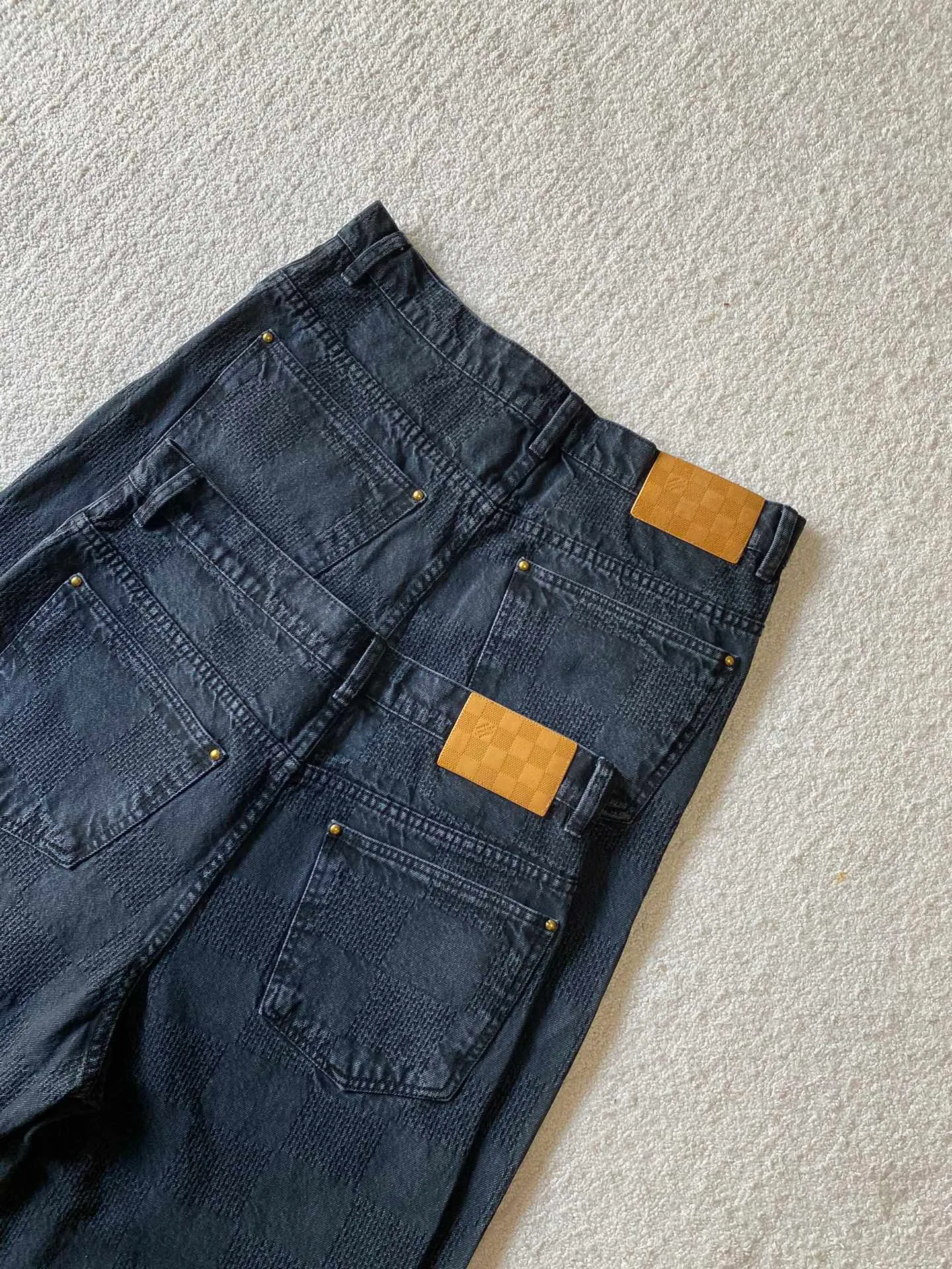 LV black checkerboard denim straight trousers ⚠️Original purchase, 600, skateboard straight version, Marque L. Uuitton deposee logo integrated into 3D Damier jacquard, back Damier label, sand washed distressed, topstitch sewing, placket distressed hardware closure #Logo integrated into 3D Damier jacquard 3D Damier jacquard denim fabric is an innovative fabric that combines jacquard technology and the characteristics of denim cloth. The classic plaid pattern is combined with 3D jacquard technology to weave three-dimensional patterns on the fabric through a loom.  The fabric presents an exquisite plaid pattern in appearance, and the pattern is made three-dimensional and layered through jacquard technology. At the same time, it retains the original tough, wear-resistant and durable properties of denim, making the clothes more durable.  # Sandwashed, Faded and Distressed Effect Sandwashed, faded and distressed denim fabric is a specially treated denim fabric that exhibits a whitened and distressed effect. This fabric uses a sand-washing process and special dyeing technology to create a natural wear and fading effect on the denim after washing, making it look more vintage and historical.  #skateboard straight jeans version Skateboard jeans are usually designed to be looser to accommodate the large movements and squatting postures during skateboarding. Jeans have a straight shape and a consistent width from hip to hem. Suitable for all body types, these straight-leg skateboard pants are designed with comfort and freedom in mind for skateboarding.