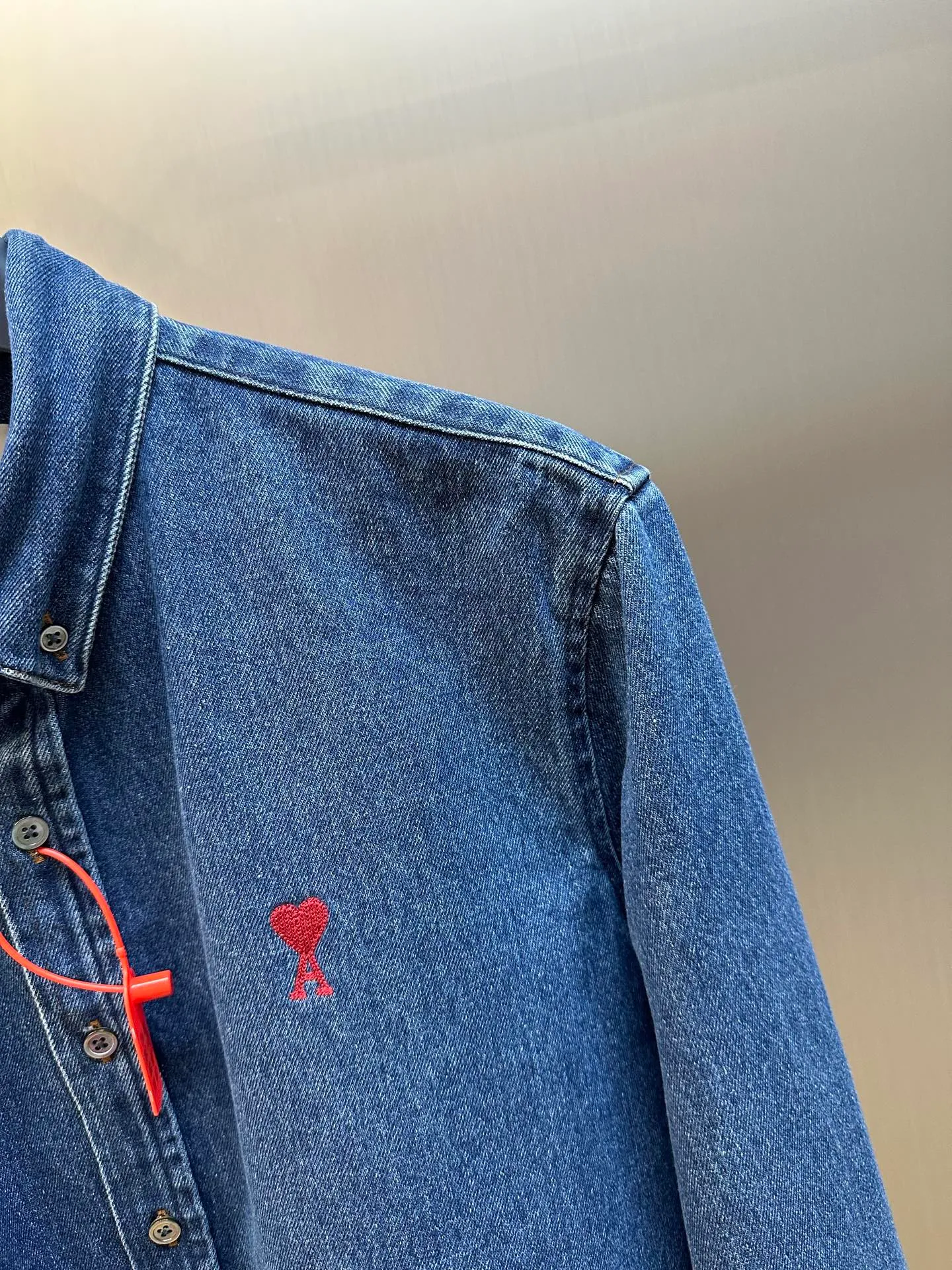 🅿️480 Ami Paris denim shirt jacket. Customized cotton essence denim fabric with a deep denim blue background and a bright red heart on the chest, injecting agility and elegance into the tough denim.  Using sand-fried hand-rubbing technology, the surface of the denim material will be naturally faded and worn by processing on a sand-fried sand machine. Then, special tools are used to physically damage the surface of the jeans by hand, maintaining the original texture and details while increasing its uniqueness. Stir-fried snowballs, stir-fried salt, specially prepare the corresponding solution, add a certain amount of dye, soak the denim material in it to absorb the solvent, and then scrub and dry it to further fade and oxidize it.  size：s m l xl
