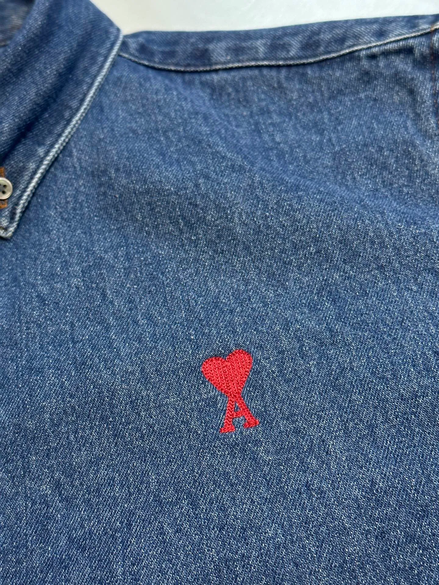 🅿️480 Ami Paris denim shirt jacket. Customized cotton essence denim fabric with a deep denim blue background and a bright red heart on the chest, injecting agility and elegance into the tough denim.  Using sand-fried hand-rubbing technology, the surface of the denim material will be naturally faded and worn by processing on a sand-fried sand machine. Then, special tools are used to physically damage the surface of the jeans by hand, maintaining the original texture and details while increasing its uniqueness. Stir-fried snowballs, stir-fried salt, specially prepare the corresponding solution, add a certain amount of dye, soak the denim material in it to absorb the solvent, and then scrub and dry it to further fade and oxidize it.  size：s m l xl