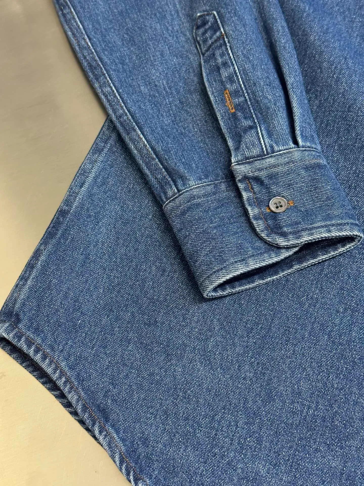 🅿️480 Ami Paris denim shirt jacket. Customized cotton essence denim fabric with a deep denim blue background and a bright red heart on the chest, injecting agility and elegance into the tough denim.  Using sand-fried hand-rubbing technology, the surface of the denim material will be naturally faded and worn by processing on a sand-fried sand machine. Then, special tools are used to physically damage the surface of the jeans by hand, maintaining the original texture and details while increasing its uniqueness. Stir-fried snowballs, stir-fried salt, specially prepare the corresponding solution, add a certain amount of dye, soak the denim material in it to absorb the solvent, and then scrub and dry it to further fade and oxidize it.  size：s m l xl