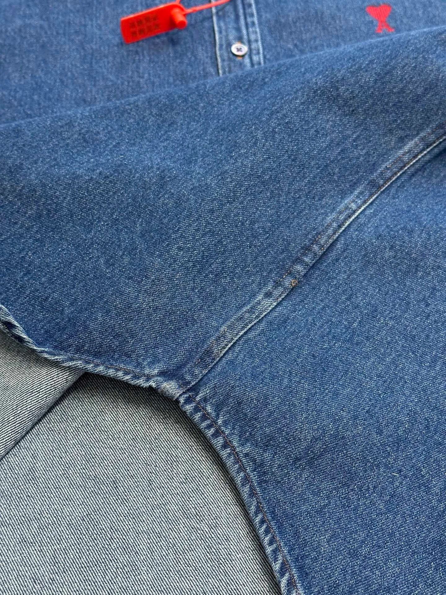 🅿️480 Ami Paris denim shirt jacket. Customized cotton essence denim fabric with a deep denim blue background and a bright red heart on the chest, injecting agility and elegance into the tough denim.  Using sand-fried hand-rubbing technology, the surface of the denim material will be naturally faded and worn by processing on a sand-fried sand machine. Then, special tools are used to physically damage the surface of the jeans by hand, maintaining the original texture and details while increasing its uniqueness. Stir-fried snowballs, stir-fried salt, specially prepare the corresponding solution, add a certain amount of dye, soak the denim material in it to absorb the solvent, and then scrub and dry it to further fade and oxidize it.  size：s m l xl