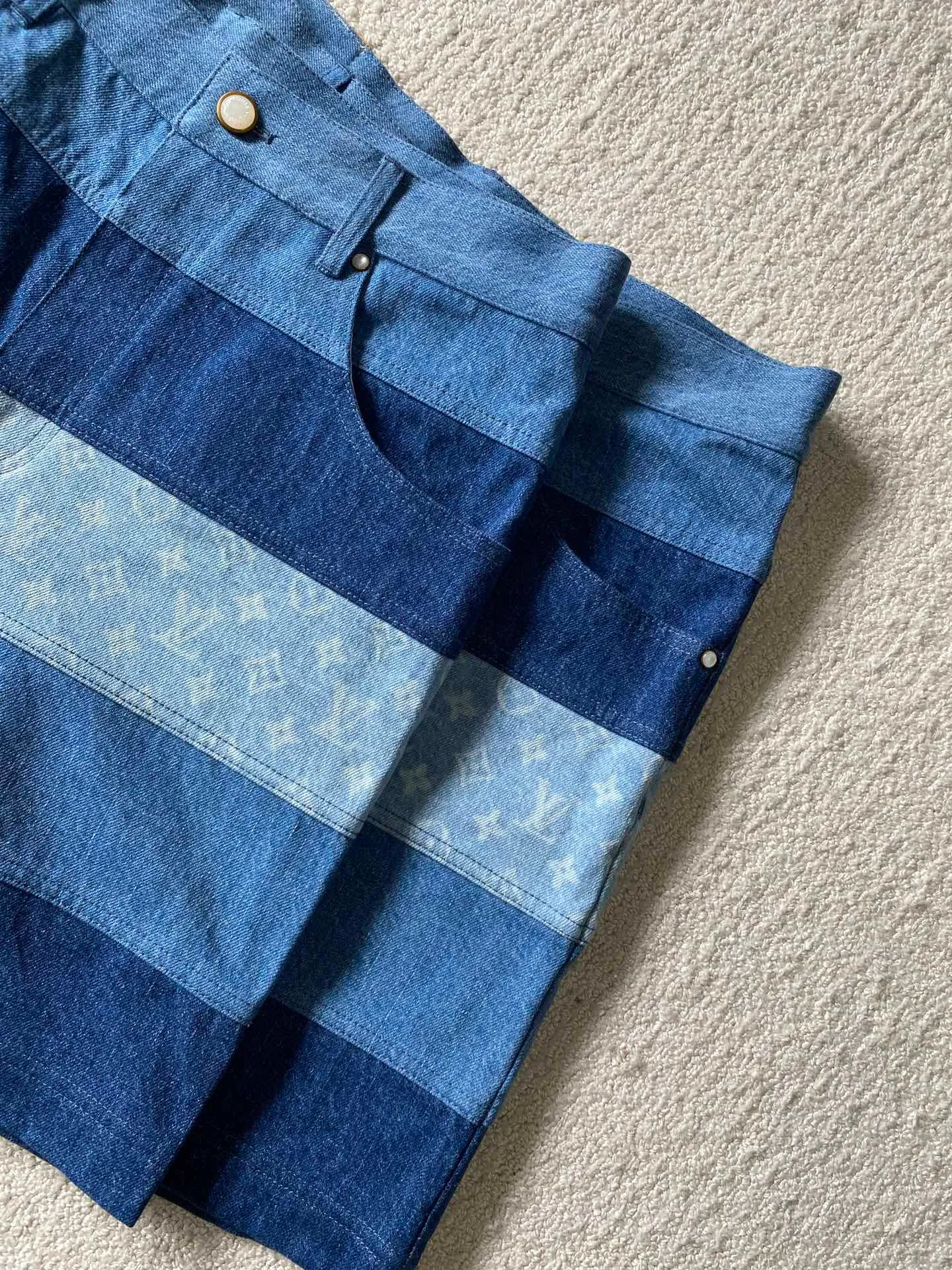LV denim patchwork shorts ⚠️Original purchase: 500; soft denim fabric, casual fit, patchwork ribbons with Monogram print, Damier nubuck label on the back, MarqueL.Uuitton deposee logo, pearlescent buttons, pearlescent studs, full set of accessories #customized denim shirt fabric The warp yarns of customized denim fabrics are dyed indigo and the weft yarns are kept white. This results in the denim fabric being indigo blue on the front and white on the back. This fabric with a denim structure is created based on the original board production process. In addition to its thick texture, it also has good breathability.  #Patchwork Ribbon Layout Monogram Print The design style of presbyopia elements in the patchwork position is made using laser printing technology. The laser printing process is an advanced printing technology that uses high-energy laser beams to directly evaporate dyes into a gaseous state and spray the dyes onto the fabric through airflow to form the desired pattern. Achieve fine pattern output and ensure the clarity and fineness of printed patterns. After printing, the fabric is dried and fixed to ensure that the dye is firm and does not fade.  #patchwork stripes patchwork patchwork clothing technology connects fabrics of different colors together through specific sewing methods to create unique visual effects and increase the complexity, artistry and layering of clothing. Pattern sewing technology restores the pattern splicing process, restores stitch length, stitch density and other parameters, as well as the correct sewing methods and steps.  # Suede leather printing with hardware accessories. The leather grid on the waist is matched with LV hardware. The original leather brand has an iron mold pattern in the same color. It is made of genuine first-layer cowhide suede. The quality is different from synthetic leather. The placket zipper opening and closing design, a full set of molded custom-made pearlescent button accessories, and clear and delicate engravings; the basic accessories are fully equipped.