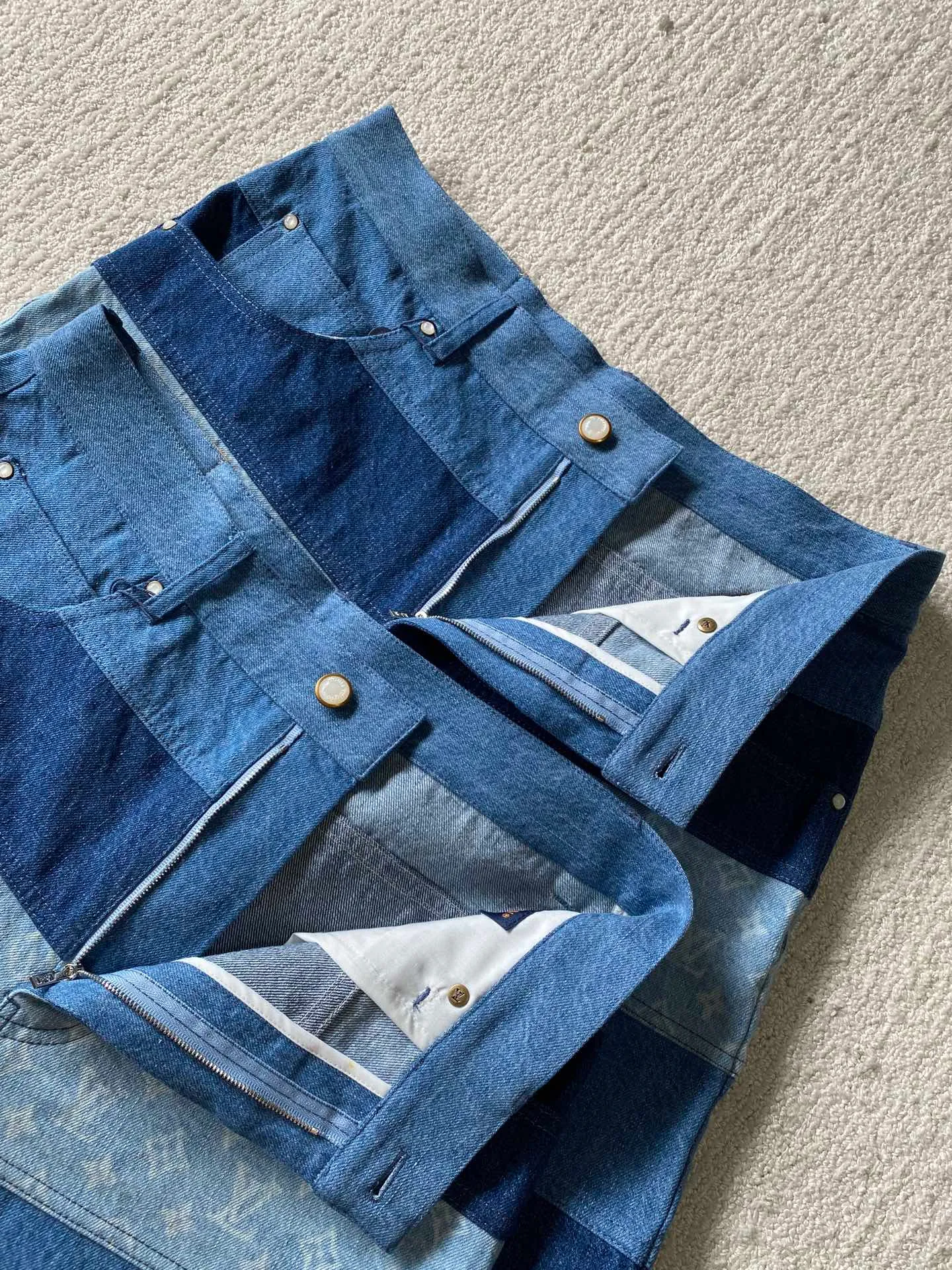 LV denim patchwork shorts ⚠️Original purchase: 500; soft denim fabric, casual fit, patchwork ribbons with Monogram print, Damier nubuck label on the back, MarqueL.Uuitton deposee logo, pearlescent buttons, pearlescent studs, full set of accessories #customized denim shirt fabric The warp yarns of customized denim fabrics are dyed indigo and the weft yarns are kept white. This results in the denim fabric being indigo blue on the front and white on the back. This fabric with a denim structure is created based on the original board production process. In addition to its thick texture, it also has good breathability.  #Patchwork Ribbon Layout Monogram Print The design style of presbyopia elements in the patchwork position is made using laser printing technology. The laser printing process is an advanced printing technology that uses high-energy laser beams to directly evaporate dyes into a gaseous state and spray the dyes onto the fabric through airflow to form the desired pattern. Achieve fine pattern output and ensure the clarity and fineness of printed patterns. After printing, the fabric is dried and fixed to ensure that the dye is firm and does not fade.  #patchwork stripes patchwork patchwork clothing technology connects fabrics of different colors together through specific sewing methods to create unique visual effects and increase the complexity, artistry and layering of clothing. Pattern sewing technology restores the pattern splicing process, restores stitch length, stitch density and other parameters, as well as the correct sewing methods and steps.  # Suede leather printing with hardware accessories. The leather grid on the waist is matched with LV hardware. The original leather brand has an iron mold pattern in the same color. It is made of genuine first-layer cowhide suede. The quality is different from synthetic leather. The placket zipper opening and closing design, a full set of molded custom-made pearlescent button accessories, and clear and delicate engravings; the basic accessories are fully equipped.