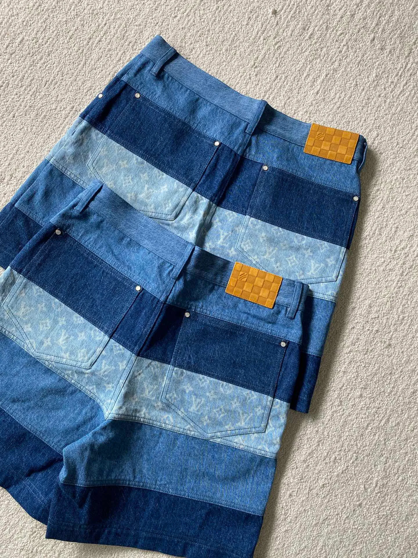 LV denim patchwork shorts ⚠️Original purchase: 500; soft denim fabric, casual fit, patchwork ribbons with Monogram print, Damier nubuck label on the back, MarqueL.Uuitton deposee logo, pearlescent buttons, pearlescent studs, full set of accessories #customized denim shirt fabric The warp yarns of customized denim fabrics are dyed indigo and the weft yarns are kept white. This results in the denim fabric being indigo blue on the front and white on the back. This fabric with a denim structure is created based on the original board production process. In addition to its thick texture, it also has good breathability.  #Patchwork Ribbon Layout Monogram Print The design style of presbyopia elements in the patchwork position is made using laser printing technology. The laser printing process is an advanced printing technology that uses high-energy laser beams to directly evaporate dyes into a gaseous state and spray the dyes onto the fabric through airflow to form the desired pattern. Achieve fine pattern output and ensure the clarity and fineness of printed patterns. After printing, the fabric is dried and fixed to ensure that the dye is firm and does not fade.  #patchwork stripes patchwork patchwork clothing technology connects fabrics of different colors together through specific sewing methods to create unique visual effects and increase the complexity, artistry and layering of clothing. Pattern sewing technology restores the pattern splicing process, restores stitch length, stitch density and other parameters, as well as the correct sewing methods and steps.  # Suede leather printing with hardware accessories. The leather grid on the waist is matched with LV hardware. The original leather brand has an iron mold pattern in the same color. It is made of genuine first-layer cowhide suede. The quality is different from synthetic leather. The placket zipper opening and closing design, a full set of molded custom-made pearlescent button accessories, and clear and delicate engravings; the basic accessories are fully equipped.