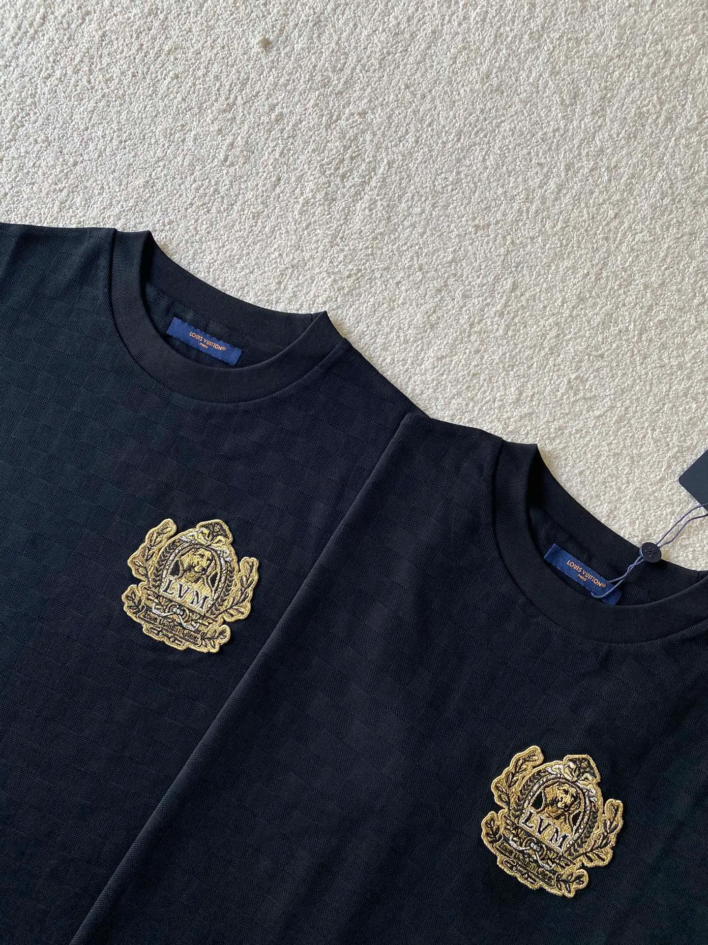 LV Golden Dog Chapter Round Neck Short Sleeve ⚠️Original purchase, 750; concealed jacquard fabric, standard version, full Damier jacquard pique, embellished with Dog Blason patch on the chest and embroidered handwritten Louis Vuitton logo # # on the back. Fully silk jacquard fabric, using 50S double-stranded silk, 210g; with 32S double yarn thread, 300g. The smooth jacquard fabric uses silk threads with better gloss as warp and weft threads, and uses complex jacquard technology to weave delicate and exquisite triangular patterns on the entire fabric. The fabric not only has a beautiful appearance and feel, but also has an overall higher quality feel. The silk jacquard fabric design adds a unique charm to the product through exquisite patterns and textures.  # The chest is embellished with Dog Blason patches and embroidered seals. The logo is made of imported custom-made embroidery thread. The glossy mercerized embroidery thread is dyed to give it a uniform and glossy finish. The exquisite embroidery machine combines complex embroidery needlework and fine detail processing to create a three-dimensional micro-relief embroidery effect.  Gold thread needle embroidery is a delicate and decorative embroidery technique. It is made of metal alloy threads with tight stitches, bright colors and high gloss. Wrap the gold wire around the spool, making sure the thread ends are neat and easy to manipulate to create a tight stitch.  # Imported embroidery thread plain embroidery technology. The handwritten embroidery is designed based on the original size and size to restore the overall three-dimensional visual effect. Using linen embroidery thread combined with encrypted processing, the embroidery body has a subtle matte visual texture; the embroidery effect is three-dimensional and full. The embroidery is very fine, the stitches are dense, the fonts are clear and the lines and three-dimensional feel are strong.  # Straight round neck version. Standard H hanging version, with shoulder-length design. The vertical version emphasizes that the width of the shoulders, waist, and hem are basically the same, and it is simple and loose. The short sleeves are tailored to fit the body of the wearer. At the same time, the neckline, cuffs and hem of the short sleeves are all designed with double lines.