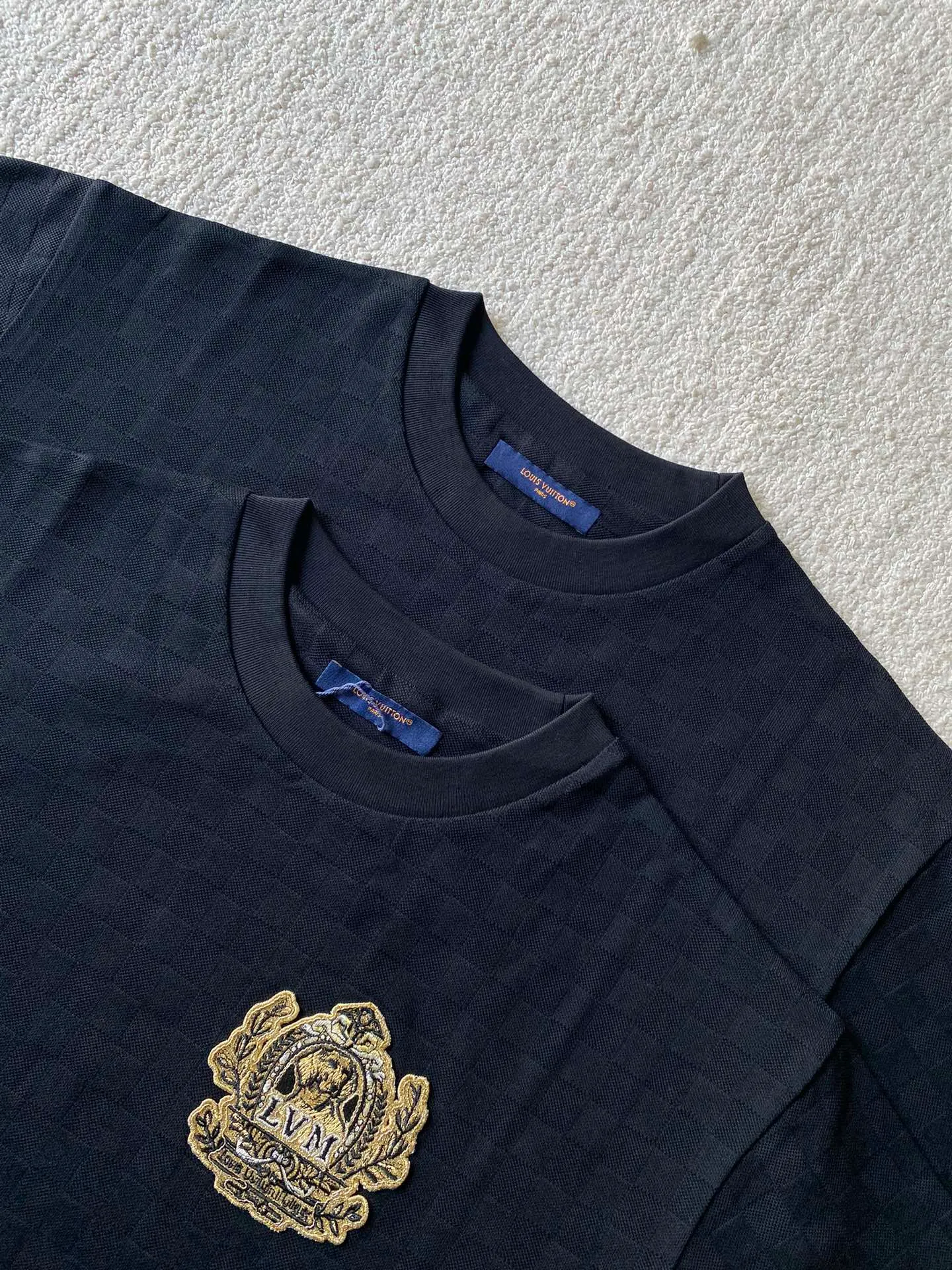 LV Golden Dog Chapter Round Neck Short Sleeve ⚠️Original purchase, 750; concealed jacquard fabric, standard version, full Damier jacquard pique, embellished with Dog Blason patch on the chest and embroidered handwritten Louis Vuitton logo # # on the back. Fully silk jacquard fabric, using 50S double-stranded silk, 210g; with 32S double yarn thread, 300g. The smooth jacquard fabric uses silk threads with better gloss as warp and weft threads, and uses complex jacquard technology to weave delicate and exquisite triangular patterns on the entire fabric. The fabric not only has a beautiful appearance and feel, but also has an overall higher quality feel. The silk jacquard fabric design adds a unique charm to the product through exquisite patterns and textures.  # The chest is embellished with Dog Blason patches and embroidered seals. The logo is made of imported custom-made embroidery thread. The glossy mercerized embroidery thread is dyed to give it a uniform and glossy finish. The exquisite embroidery machine combines complex embroidery needlework and fine detail processing to create a three-dimensional micro-relief embroidery effect.  Gold thread needle embroidery is a delicate and decorative embroidery technique. It is made of metal alloy threads with tight stitches, bright colors and high gloss. Wrap the gold wire around the spool, making sure the thread ends are neat and easy to manipulate to create a tight stitch.  # Imported embroidery thread plain embroidery technology. The handwritten embroidery is designed based on the original size and size to restore the overall three-dimensional visual effect. Using linen embroidery thread combined with encrypted processing, the embroidery body has a subtle matte visual texture; the embroidery effect is three-dimensional and full. The embroidery is very fine, the stitches are dense, the fonts are clear and the lines and three-dimensional feel are strong.  # Straight round neck version. Standard H hanging version, with shoulder-length design. The vertical version emphasizes that the width of the shoulders, waist, and hem are basically the same, and it is simple and loose. The short sleeves are tailored to fit the body of the wearer. At the same time, the neckline, cuffs and hem of the short sleeves are all designed with double lines.