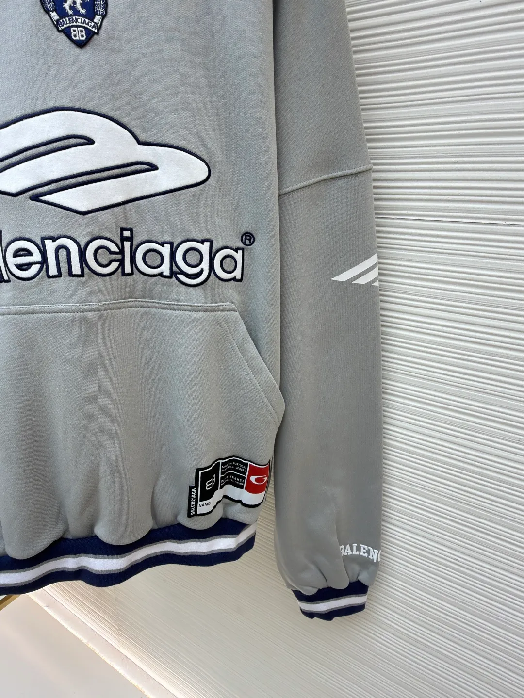 Balenciaga 3B football Polo hoodie ●Original version: purchased and developed by 10767 ●Item number: 1682334-B05 ●Fabric: cotton fabric ●Technology: embroidery applique production ●Color: gray ●Version: loose fit ●Weight: about 885 grams ●Size: XS-S-M-L ●Description: The neckline adopts a half-open button design and is decorated with metal badges to enhance the layered look; the main body of the garment presents the brand logo through three-dimensional foam printing technology, and the grayscale gradient effect enhances the visual texture. The cuffs and hem are edged with contrasting ribbing, which has moderate elasticity and is not easily deformed; a collage label is embedded in the left hem, and the details echo the brand's street style. The partial logo embroidery on the shoulders and cuffs echoes the main pattern. The overall craftsmanship takes into account practical wearability and brand recognition, making it suitable for daily casual or trendy looks. The overall wiring is straight and delicate, the fabric is comfortable and soft, and the color is consistent without color difference. It can be matched with the same style to create a fashionable look and control various occasions. Customized accessories, complete with three standards, same style for men and women!