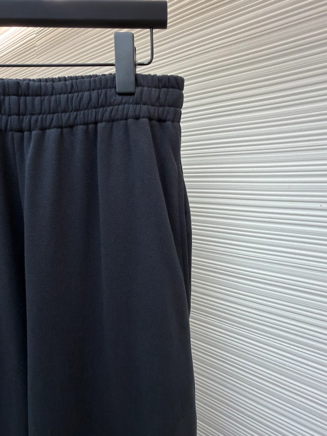 Balenciaga side webbing trousers ●Original version: Purchased and developed by 7858 ●Item number: 1682188-A95 ●Fabric: cotton fabric ●Technology: printing production ●Color: black ●Version: loose fit ●Weight: about 745 grams ●Size: XS-S-M-L ●Description: This black casual trousers with side straps shows ingenuity in craftsmanship. The trousers are made of high-density twill knitted fabric, which has undergone pre-shrunk treatment and high-temperature shaping process to ensure that the fabric is not easy to pill, deform and has an outstanding drape feeling. It also has good breathability and anti-wrinkle properties. The waist is designed with a high-elastic spandex drawstring, which is reinforced through precise four-line seaming technology. The drawstring perforations are equipped with metal air holes, which not only improves durability but also adds detailed texture. The side decorative belt is a custom-made jacquard webbing, woven with 72 stitches of high-density on a computerized jacquard machine. The pattern texture is clear and three-dimensional. The webbing and the trousers are spliced ​​together through a flat car synchronous sewing process. The stitches are even and fine and the spacing is controlled within 0.8cm, eliminating jumpers and off-thread problems. The trouser legs are hemmed using a seamless process and are reinforced with inner linings. The overall tailoring follows ergonomics and uses three-dimensional tailoring technology to make the trousers fit the body shape. Each process undergoes three quality control inspections. From fabric cutting to finished product sewing, dimensional accuracy and process details are strictly controlled throughout the process to create casual trousers with both texture and practical wearability. The overall wiring is straight and delicate, the fabric is comfortable and soft, and the color is consistent without color difference. It can be matched with the same style to create a fashionable look and control various occasions. Customized accessories, complete with three standards, same style for men and women!