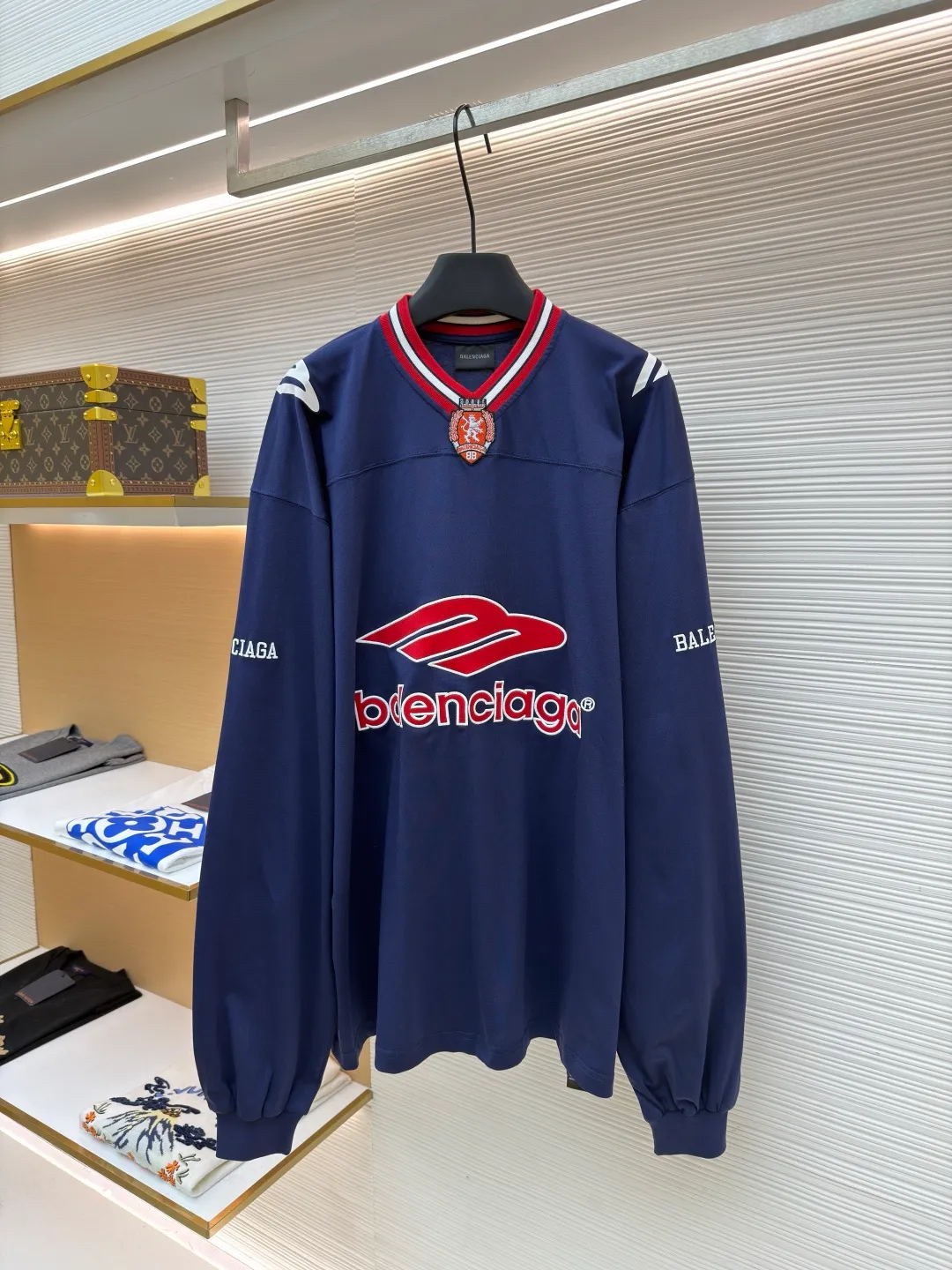 Balenciaga team series V-neck long sleeves ●Original version: purchased and developed by 8016 ●Item number: 1682072-A55 ●Fabric: plain knitted compact cotton fabric ●Technology: glue printing ●Color: blue ●Version: loose version ●Weight: about 375 grams ●Size: XS-S-M-L ●Description: The main body is made of 24-count special woven compact cotton with a weight of 185g/㎡. Compact spinning technology is applied in the spinning process, which significantly reduces yarn hairiness and makes the yarn smoother and stronger. This gives the fabric an unusually dense structure, a smooth and smooth surface, and excellent pilling resistance, while retaining the softness and breathability of pure cotton. The weight of 185g is light to middleweight, ensuring that the clothing is light, drapeable and can move freely. It is very suitable for creating a long-sleeved shirt that combines sportiness with daily comfort. The V-neck part is made of two different colors of high-elastic rib fabrics. The process step is to first weave ribbed belts of two colors separately, and then through precise cutting and splicing, form a V-shaped neckline with sharp color contrast. It breaks the monotony of the solid color body, uses strong color contrast to create a young and energetic visual focus, and optimizes the neck line. The pattern is pre-cut and formed into patches on fabrics of different materials or colors, and then covered on the body. Finally, high-density embroidery thread is used to fix the edges and outline the internal details. Its function is to create patterns with bright colors, strong texture contrast, three-dimensionality and durability. The edges of the pattern are strong and not easy to wear. A special elastic paste is screen-printed on the sleeves to create brightly colored patterns with a slightly coated feel. The elastic paste ensures that the printed area can stretch with the fabric without cracking. It forms a texture contrast between one flat and one convex with the three-dimensional sense of appliqué, which increases the interest and complexity of the design. The overall wiring is straight and delicate, the fabric is comfortable and soft, and the color is consistent without color difference. It can be matched with the same style to create a fashionable look and control various occasions. Customized accessories, complete with three standards, same style for men and women!