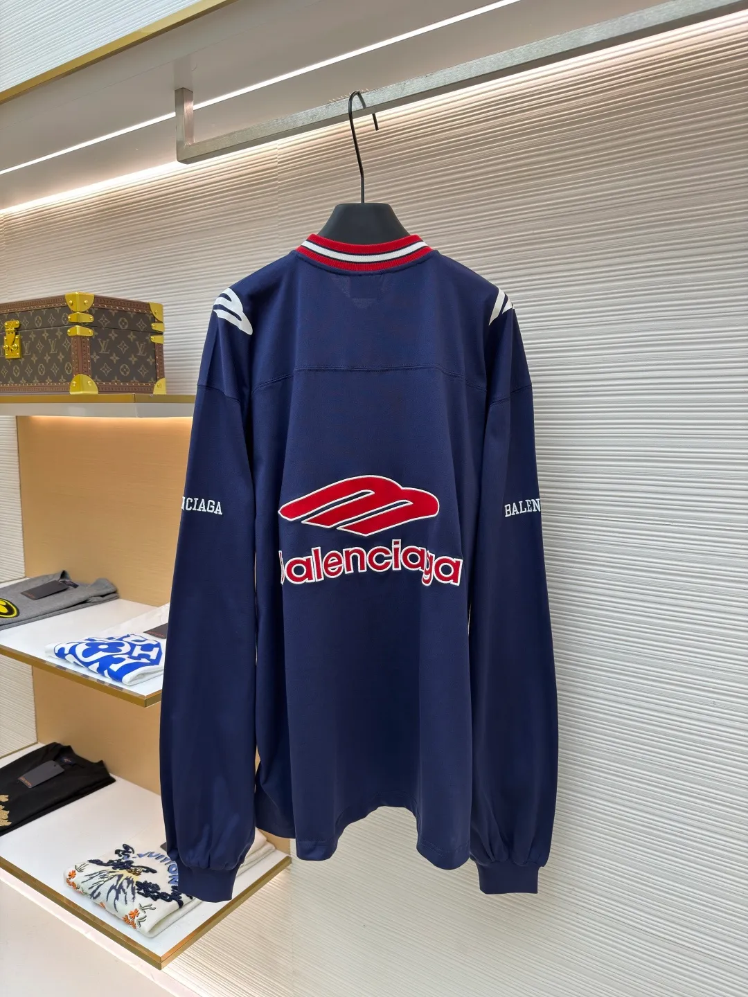 Balenciaga team series V-neck long sleeves ●Original version: purchased and developed by 8016 ●Item number: 1682072-A55 ●Fabric: plain knitted compact cotton fabric ●Technology: glue printing ●Color: blue ●Version: loose version ●Weight: about 375 grams ●Size: XS-S-M-L ●Description: The main body is made of 24-count special woven compact cotton with a weight of 185g/㎡. Compact spinning technology is applied in the spinning process, which significantly reduces yarn hairiness and makes the yarn smoother and stronger. This gives the fabric an unusually dense structure, a smooth and smooth surface, and excellent pilling resistance, while retaining the softness and breathability of pure cotton. The weight of 185g is light to middleweight, ensuring that the clothing is light, drapeable and can move freely. It is very suitable for creating a long-sleeved shirt that combines sportiness with daily comfort. The V-neck part is made of two different colors of high-elastic rib fabrics. The process step is to first weave ribbed belts of two colors separately, and then through precise cutting and splicing, form a V-shaped neckline with sharp color contrast. It breaks the monotony of the solid color body, uses strong color contrast to create a young and energetic visual focus, and optimizes the neck line. The pattern is pre-cut and formed into patches on fabrics of different materials or colors, and then covered on the body. Finally, high-density embroidery thread is used to fix the edges and outline the internal details. Its function is to create patterns with bright colors, strong texture contrast, three-dimensionality and durability. The edges of the pattern are strong and not easy to wear. A special elastic paste is screen-printed on the sleeves to create brightly colored patterns with a slightly coated feel. The elastic paste ensures that the printed area can stretch with the fabric without cracking. It forms a texture contrast between one flat and one convex with the three-dimensional sense of appliqué, which increases the interest and complexity of the design. The overall wiring is straight and delicate, the fabric is comfortable and soft, and the color is consistent without color difference. It can be matched with the same style to create a fashionable look and control various occasions. Customized accessories, complete with three standards, same style for men and women!