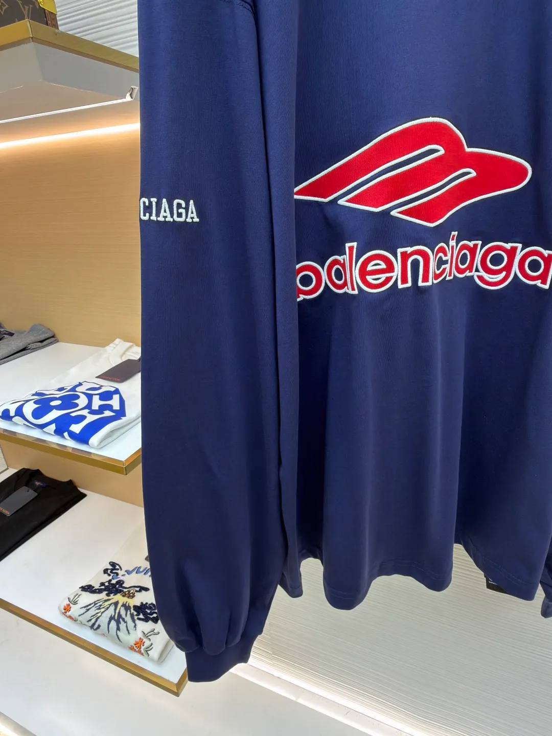 Balenciaga team series V-neck long sleeves ●Original version: purchased and developed by 8016 ●Item number: 1682072-A55 ●Fabric: plain knitted compact cotton fabric ●Technology: glue printing ●Color: blue ●Version: loose version ●Weight: about 375 grams ●Size: XS-S-M-L ●Description: The main body is made of 24-count special woven compact cotton with a weight of 185g/㎡. Compact spinning technology is applied in the spinning process, which significantly reduces yarn hairiness and makes the yarn smoother and stronger. This gives the fabric an unusually dense structure, a smooth and smooth surface, and excellent pilling resistance, while retaining the softness and breathability of pure cotton. The weight of 185g is light to middleweight, ensuring that the clothing is light, drapeable and can move freely. It is very suitable for creating a long-sleeved shirt that combines sportiness with daily comfort. The V-neck part is made of two different colors of high-elastic rib fabrics. The process step is to first weave ribbed belts of two colors separately, and then through precise cutting and splicing, form a V-shaped neckline with sharp color contrast. It breaks the monotony of the solid color body, uses strong color contrast to create a young and energetic visual focus, and optimizes the neck line. The pattern is pre-cut and formed into patches on fabrics of different materials or colors, and then covered on the body. Finally, high-density embroidery thread is used to fix the edges and outline the internal details. Its function is to create patterns with bright colors, strong texture contrast, three-dimensionality and durability. The edges of the pattern are strong and not easy to wear. A special elastic paste is screen-printed on the sleeves to create brightly colored patterns with a slightly coated feel. The elastic paste ensures that the printed area can stretch with the fabric without cracking. It forms a texture contrast between one flat and one convex with the three-dimensional sense of appliqué, which increases the interest and complexity of the design. The overall wiring is straight and delicate, the fabric is comfortable and soft, and the color is consistent without color difference. It can be matched with the same style to create a fashionable look and control various occasions. Customized accessories, complete with three standards, same style for men and women!
