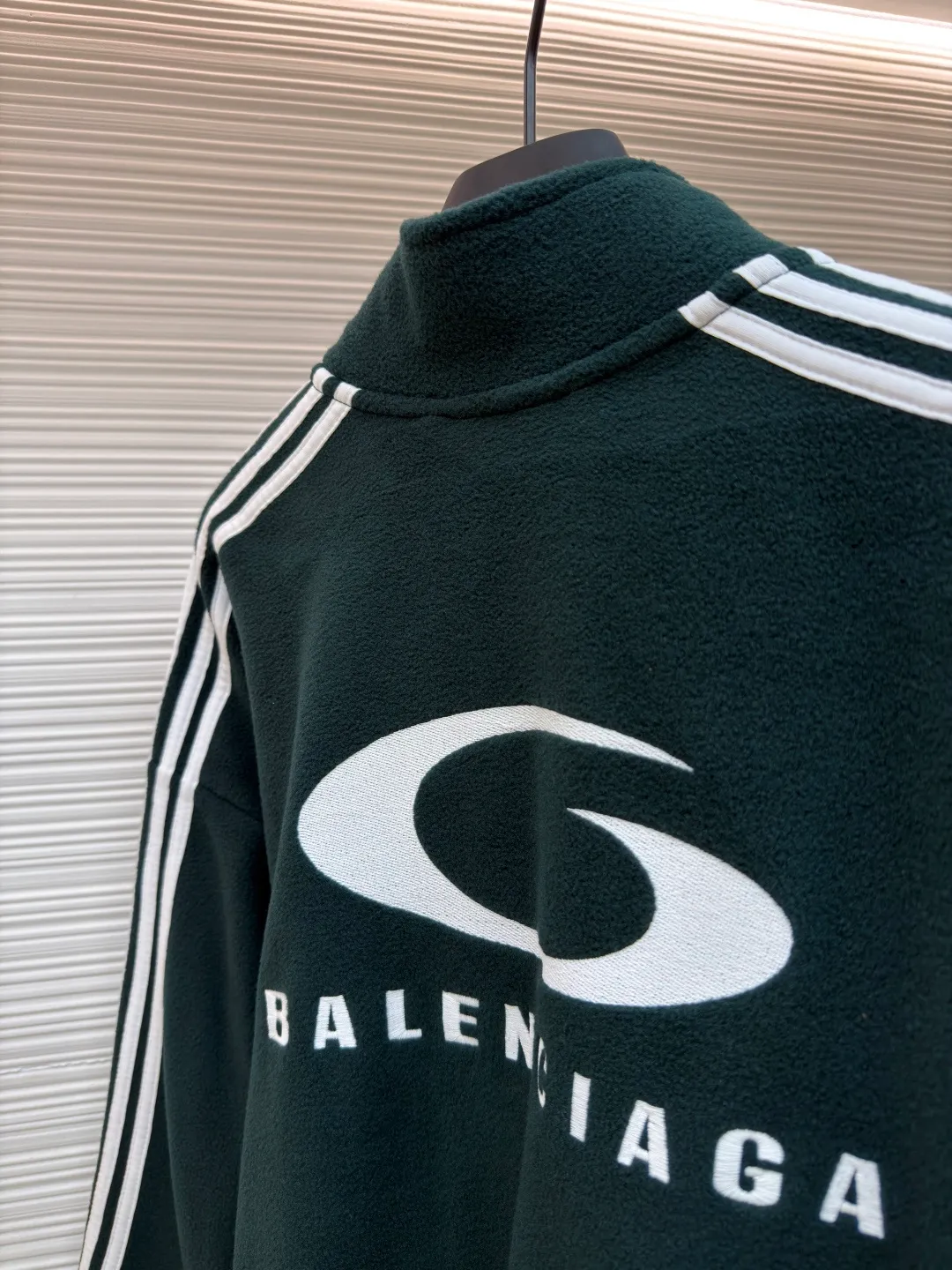 Balenciaga stand-up collar zipper jacket with embroidered sleeves ●Original version: Purchased and developed for 16500 ●Item number: 1680949-B25 ●Fabric: polar fleece fabric ●Technology: knitted production ●Version: Loose fit ●Weight: about 735 grams ●Size: XS-S-M-L ●Description: High-performance polar fleece knitted fabric is known for its excellent warmth retention and light texture. Through a special brushing process, a dense and rich velvet structure is formed on the surface of the fabric, which effectively locks in still air and achieves efficient heat insulation. The warmth retention per unit weight is better than that of traditional knitted materials. At the same time, its fiber gaps ensure that moisture can be exported in time, taking into account breathability. The fabric is usually treated with anti-static and water-repellent treatments to enhance practical functions, and has excellent ductility and anti-pilling properties. It feels soft and fluffy, and does not feel restrictive when moving. Using high-density stitching and multi-color embroidery thread, the pattern has clear edges and three-dimensional fullness; it is made with the overall tatami embroidery technology. To customize the embroidery thread material according to the pattern and color, you need to choose a suitable rice mat as the base material for embroidery to ensure that its surface is flat, smooth and suitable for embroidery. Draw line outlines on the fabric according to the embroidery pattern so that the outline can be accurately followed during embroidery. The contrasting piping on the sleeves is precisely stitched with hemming technology to strengthen the contour lines and improve wear resistance; the solid color fabric and white contrasting design enhance the visual impact. The gathered cuffs and waist are made of high-elastic rib material to enhance the fit and prevent the intrusion of cold wind. It is equipped with a double-ended zipper to achieve flexible opening and closing. The two zippered diagonal pockets take into account storage security and smooth styling, reflecting practical details. The silhouette is both unisex and unisex, with a gathered waist and straight body that balances looseness and slim fit. The high collar design extends the neck protection, echoing the theme of sports protection; the overall minimalist outline highlights the visual focus of embroidery and piping, transforming functional details into design elements, perfectly integrating sports genes and street art style. The overall wiring is straight and delicate, the fabric is comfortable and soft, and the color is consistent without color difference. It can be matched with the same style to create a fashionable look and control various occasions. Customized accessories, complete with three standards, same style for men and women!