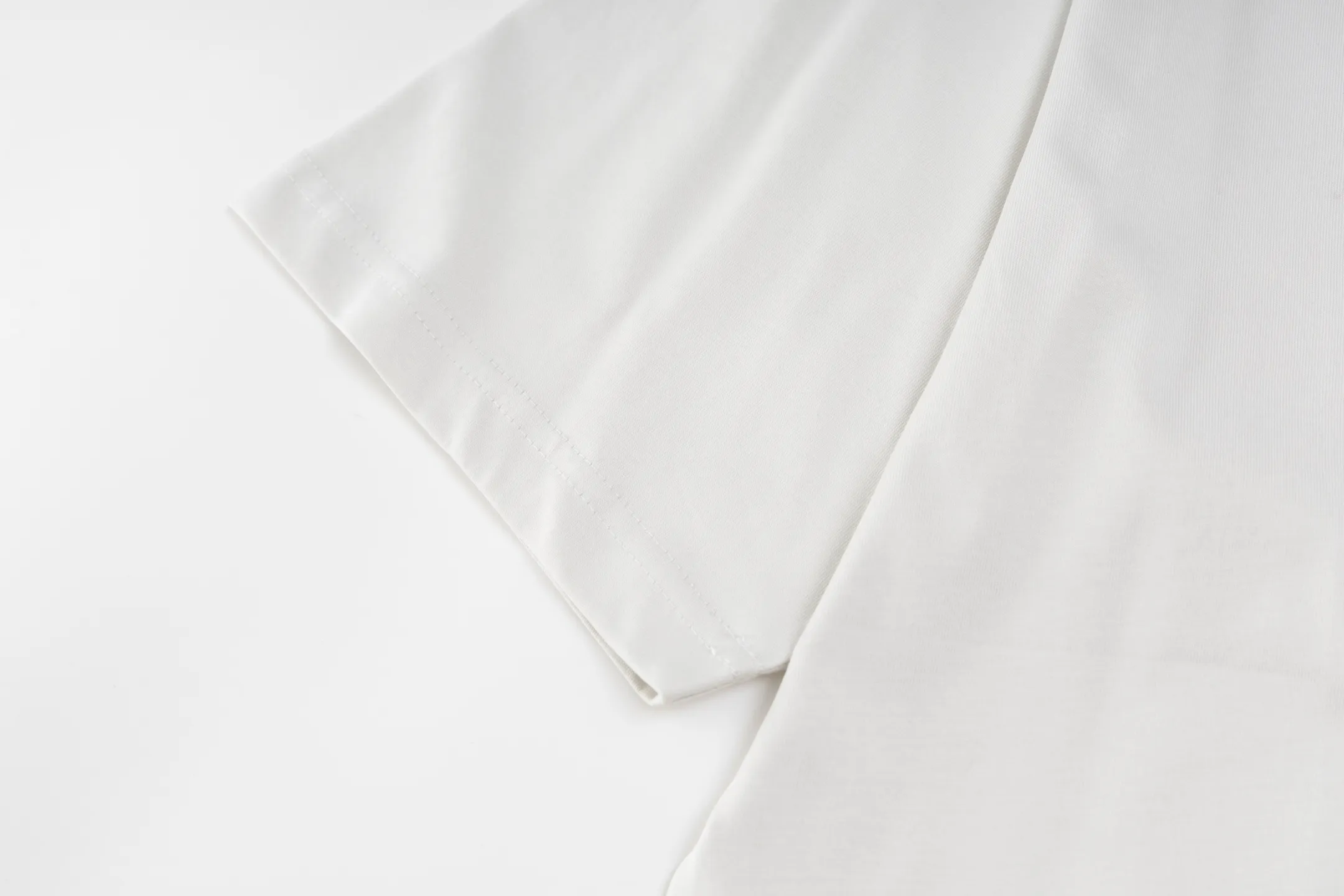 🅿️290 Exclusive supply] BLCG 25FW badge printed short sleeves (white) The fabric is made of 24S 185g double yarn special textile compact cotton, and the rib is made of 32S 340g double yarn stretch rib. The structure of pure cotton fabric is plain weave. The surface of the fabric is smooth and delicate, and the texture is tight. It has good moisture absorption, breathability and comfort, and can keep you dry and comfortable. Due to its tight spinning process, it also has good wrinkle resistance and durability, making it suitable for long-term wear or use. The multi-layer superposition process of dark flower paste dots uses precision screen technology to cover the fabric with translucent printing paste through multiple layered printing. Each layer is laminated and fused with micron-level tolerances. Through subtle changes in the thickness and density of the slurry, an invisible pattern with a transition between dark and light is formed on the surface of the fabric. This technology replaces color contrast with physical accumulation, and uses the diffuse reflection of light on concave and convex surfaces to present a looming light and shadow relief effect, creating a high-end print with both visual haziness and tactile three-dimensionality, which perfectly fits the low-key and luxurious design aesthetics. Size:XS-S-M-L