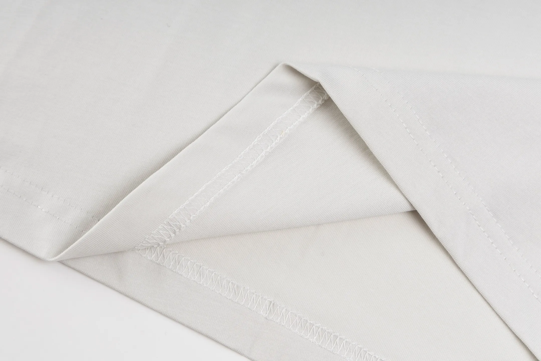 🅿️290 Exclusive supply] BLCG 25FW badge printed short sleeves (white) The fabric is made of 24S 185g double yarn special textile compact cotton, and the rib is made of 32S 340g double yarn stretch rib. The structure of pure cotton fabric is plain weave. The surface of the fabric is smooth and delicate, and the texture is tight. It has good moisture absorption, breathability and comfort, and can keep you dry and comfortable. Due to its tight spinning process, it also has good wrinkle resistance and durability, making it suitable for long-term wear or use. The multi-layer superposition process of dark flower paste dots uses precision screen technology to cover the fabric with translucent printing paste through multiple layered printing. Each layer is laminated and fused with micron-level tolerances. Through subtle changes in the thickness and density of the slurry, an invisible pattern with a transition between dark and light is formed on the surface of the fabric. This technology replaces color contrast with physical accumulation, and uses the diffuse reflection of light on concave and convex surfaces to present a looming light and shadow relief effect, creating a high-end print with both visual haziness and tactile three-dimensionality, which perfectly fits the low-key and luxurious design aesthetics. Size:XS-S-M-L