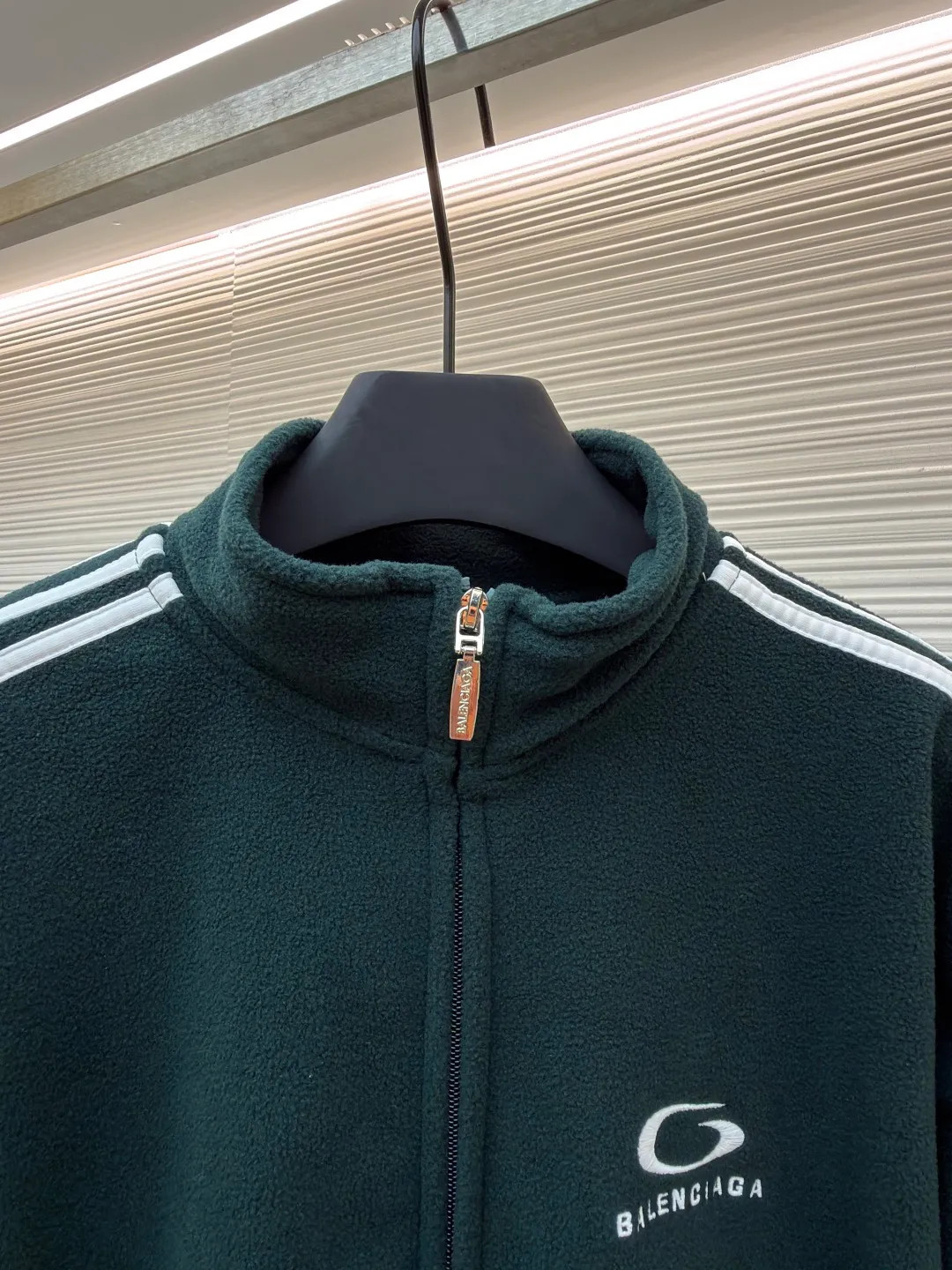 Balenciaga stand-up collar zipper jacket with embroidered sleeves ●Original version: Purchased and developed for 16500 ●Item number: 1680949-B25 ●Fabric: polar fleece fabric ●Technology: knitted production ●Version: Loose fit ●Weight: about 735 grams ●Size: XS-S-M-L ●Description: High-performance polar fleece knitted fabric is known for its excellent warmth retention and light texture. Through a special brushing process, a dense and rich velvet structure is formed on the surface of the fabric, which effectively locks in still air and achieves efficient heat insulation. The warmth retention per unit weight is better than that of traditional knitted materials. At the same time, its fiber gaps ensure that moisture can be exported in time, taking into account breathability. The fabric is usually treated with anti-static and water-repellent treatments to enhance practical functions, and has excellent ductility and anti-pilling properties. It feels soft and fluffy, and does not feel restrictive when moving. Using high-density stitching and multi-color embroidery thread, the pattern has clear edges and three-dimensional fullness; it is made with the overall tatami embroidery technology. To customize the embroidery thread material according to the pattern and color, you need to choose a suitable rice mat as the base material for embroidery to ensure that its surface is flat, smooth and suitable for embroidery. Draw line outlines on the fabric according to the embroidery pattern so that the outline can be accurately followed during embroidery. The contrasting piping on the sleeves is precisely stitched with hemming technology to strengthen the contour lines and improve wear resistance; the solid color fabric and white contrasting design enhance the visual impact. The gathered cuffs and waist are made of high-elastic rib material to enhance the fit and prevent the intrusion of cold wind. It is equipped with a double-ended zipper to achieve flexible opening and closing. The two zippered diagonal pockets take into account storage security and smooth styling, reflecting practical details. The silhouette is both unisex and unisex, with a gathered waist and straight body that balances looseness and slim fit. The high collar design extends the neck protection, echoing the theme of sports protection; the overall minimalist outline highlights the visual focus of embroidery and piping, transforming functional details into design elements, perfectly integrating sports genes and street art style. The overall wiring is straight and delicate, the fabric is comfortable and soft, and the color is consistent without color difference. It can be matched with the same style to create a fashionable look and control various occasions. Customized accessories, complete with three standards, same style for men and women!