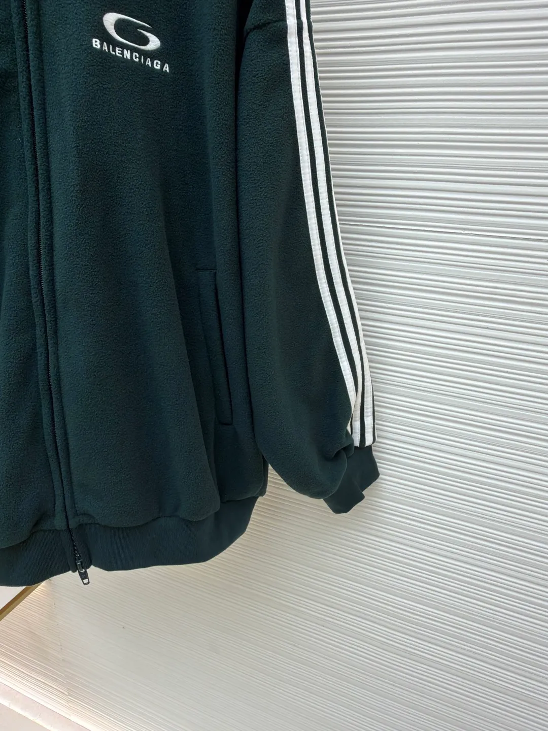 Balenciaga stand-up collar zipper jacket with embroidered sleeves ●Original version: Purchased and developed for 16500 ●Item number: 1680949-B25 ●Fabric: polar fleece fabric ●Technology: knitted production ●Version: Loose fit ●Weight: about 735 grams ●Size: XS-S-M-L ●Description: High-performance polar fleece knitted fabric is known for its excellent warmth retention and light texture. Through a special brushing process, a dense and rich velvet structure is formed on the surface of the fabric, which effectively locks in still air and achieves efficient heat insulation. The warmth retention per unit weight is better than that of traditional knitted materials. At the same time, its fiber gaps ensure that moisture can be exported in time, taking into account breathability. The fabric is usually treated with anti-static and water-repellent treatments to enhance practical functions, and has excellent ductility and anti-pilling properties. It feels soft and fluffy, and does not feel restrictive when moving. Using high-density stitching and multi-color embroidery thread, the pattern has clear edges and three-dimensional fullness; it is made with the overall tatami embroidery technology. To customize the embroidery thread material according to the pattern and color, you need to choose a suitable rice mat as the base material for embroidery to ensure that its surface is flat, smooth and suitable for embroidery. Draw line outlines on the fabric according to the embroidery pattern so that the outline can be accurately followed during embroidery. The contrasting piping on the sleeves is precisely stitched with hemming technology to strengthen the contour lines and improve wear resistance; the solid color fabric and white contrasting design enhance the visual impact. The gathered cuffs and waist are made of high-elastic rib material to enhance the fit and prevent the intrusion of cold wind. It is equipped with a double-ended zipper to achieve flexible opening and closing. The two zippered diagonal pockets take into account storage security and smooth styling, reflecting practical details. The silhouette is both unisex and unisex, with a gathered waist and straight body that balances looseness and slim fit. The high collar design extends the neck protection, echoing the theme of sports protection; the overall minimalist outline highlights the visual focus of embroidery and piping, transforming functional details into design elements, perfectly integrating sports genes and street art style. The overall wiring is straight and delicate, the fabric is comfortable and soft, and the color is consistent without color difference. It can be matched with the same style to create a fashionable look and control various occasions. Customized accessories, complete with three standards, same style for men and women!