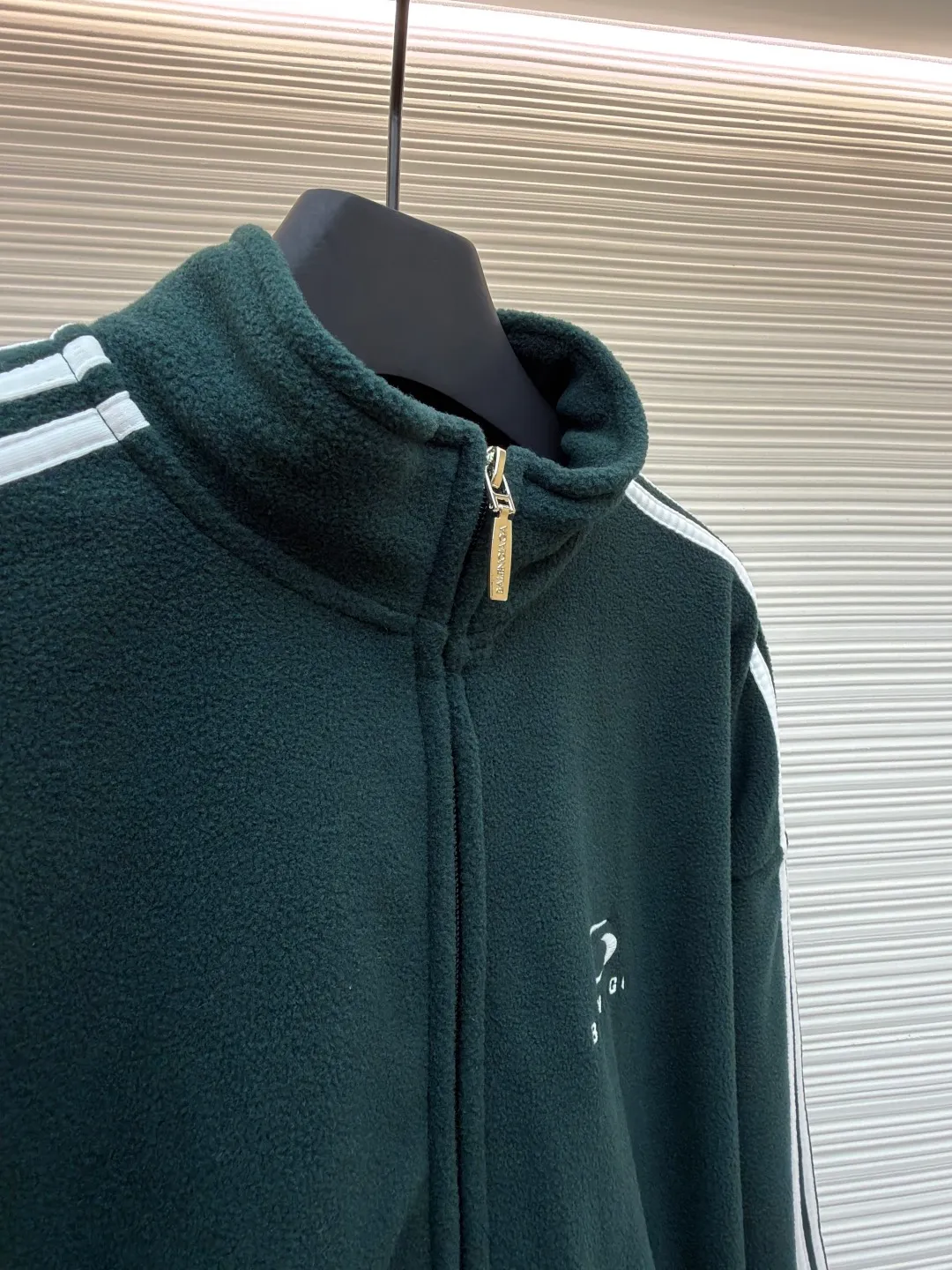 Balenciaga stand-up collar zipper jacket with embroidered sleeves ●Original version: Purchased and developed for 16500 ●Item number: 1680949-B25 ●Fabric: polar fleece fabric ●Technology: knitted production ●Version: Loose fit ●Weight: about 735 grams ●Size: XS-S-M-L ●Description: High-performance polar fleece knitted fabric is known for its excellent warmth retention and light texture. Through a special brushing process, a dense and rich velvet structure is formed on the surface of the fabric, which effectively locks in still air and achieves efficient heat insulation. The warmth retention per unit weight is better than that of traditional knitted materials. At the same time, its fiber gaps ensure that moisture can be exported in time, taking into account breathability. The fabric is usually treated with anti-static and water-repellent treatments to enhance practical functions, and has excellent ductility and anti-pilling properties. It feels soft and fluffy, and does not feel restrictive when moving. Using high-density stitching and multi-color embroidery thread, the pattern has clear edges and three-dimensional fullness; it is made with the overall tatami embroidery technology. To customize the embroidery thread material according to the pattern and color, you need to choose a suitable rice mat as the base material for embroidery to ensure that its surface is flat, smooth and suitable for embroidery. Draw line outlines on the fabric according to the embroidery pattern so that the outline can be accurately followed during embroidery. The contrasting piping on the sleeves is precisely stitched with hemming technology to strengthen the contour lines and improve wear resistance; the solid color fabric and white contrasting design enhance the visual impact. The gathered cuffs and waist are made of high-elastic rib material to enhance the fit and prevent the intrusion of cold wind. It is equipped with a double-ended zipper to achieve flexible opening and closing. The two zippered diagonal pockets take into account storage security and smooth styling, reflecting practical details. The silhouette is both unisex and unisex, with a gathered waist and straight body that balances looseness and slim fit. The high collar design extends the neck protection, echoing the theme of sports protection; the overall minimalist outline highlights the visual focus of embroidery and piping, transforming functional details into design elements, perfectly integrating sports genes and street art style. The overall wiring is straight and delicate, the fabric is comfortable and soft, and the color is consistent without color difference. It can be matched with the same style to create a fashionable look and control various occasions. Customized accessories, complete with three standards, same style for men and women!