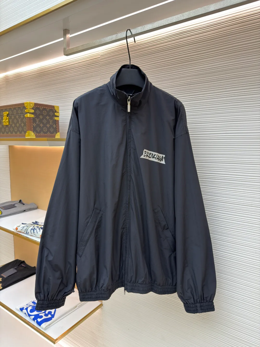 Balenciaga glue print jacket ●Original version: Purchased and developed for 20000 ●Item number: 1682403-B40 ●Fabric: woven nylon fabric ●Technology: glue printing production ●Color: black ●Version: fitted version ●Weight: about 480 grams ●Size: XS-S-M ●Description: This Balenciaga cotton blended jacket is made of 65% cotton and 35% polyester fiber blended fabric. It is first processed by a high-temperature pre-shrinking process to control the fabric shrinkage within 1% to avoid deformation after wearing and washing. The brand logo on the front of the body is made using glue printing technology. Before printing, the fabric is statically eliminated, and then the glue is tightly combined with the fabric through 150℃ high temperature printing. The pattern is clear, does not fall off and is friction-resistant. The jacket adopts a stand-up collar zipper design. The metal zipper has been treated with anti-oxidation plating and is smooth and easy to pull. The cuffs and hem are made of elastic ribbing. The rib weaving method is 1*1 double-needle technology, which is durable and not easy to loosen. The side seam pockets use invisible inlay technology with a stitch density of 8 stitches per centimeter. The shoulders are seamlessly taped. The overall craftsmanship takes into account the brand's iconic simple design and durability, and the details highlight the production standards of high-end clothing. The overall wiring is straight and delicate, the fabric is comfortable and soft, and the color is consistent without color difference. It can be matched with the same style to create a fashionable look and control various occasions. Customized accessories, complete with three standards, same style for men and women!