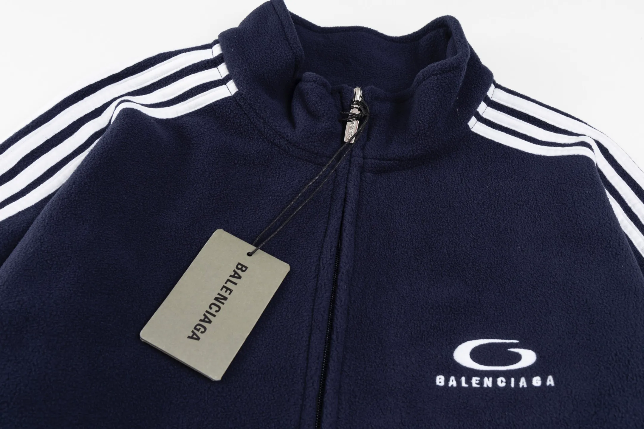 🅿️500 [Exclusive supply] BLCG ring embroidered polar fleece jacket. The fabric is made of polyester filament and passed through a circular knitting machine. The warp and weft yarns are woven into each other into a double-sided knitted structure. The front and back are flat loops. The polar fleece fabric is formed after a series of processes such as dyeing, raising, carding, shearing, and polarization. The suede texture is soft and the fiber characteristics make it almost non-absorbent. It can quickly drain sweat to the outer layer of the fabric and evaporate quickly, maintaining good breathability. The suede surface can lock the air and form a stagnant air layer around the body, effectively preventing heat loss and providing good warmth retention properties. The imported embroidery machine uses 3000 needles + 11000 needles to form a small and large loop sports icon embroidery on the front and back panels. The double-axis linear guide drives the embroidery frame, and the frame moving accuracy can reach 0.01mm/P, ensuring precise positioning of the embroidery pattern. The trim is precisely positioned along the specified contour from the cuffs to the shoulder collar seam to ensure symmetry and overall smoothness. Before actual sewing, use very fine basting stitches for pre-fixing. This step is crucial to prevent the trim from slipping, twisting, or wrinkling during the sewing process and ensuring that the final stitch is straight and perfect. Size:S/M/L/XL