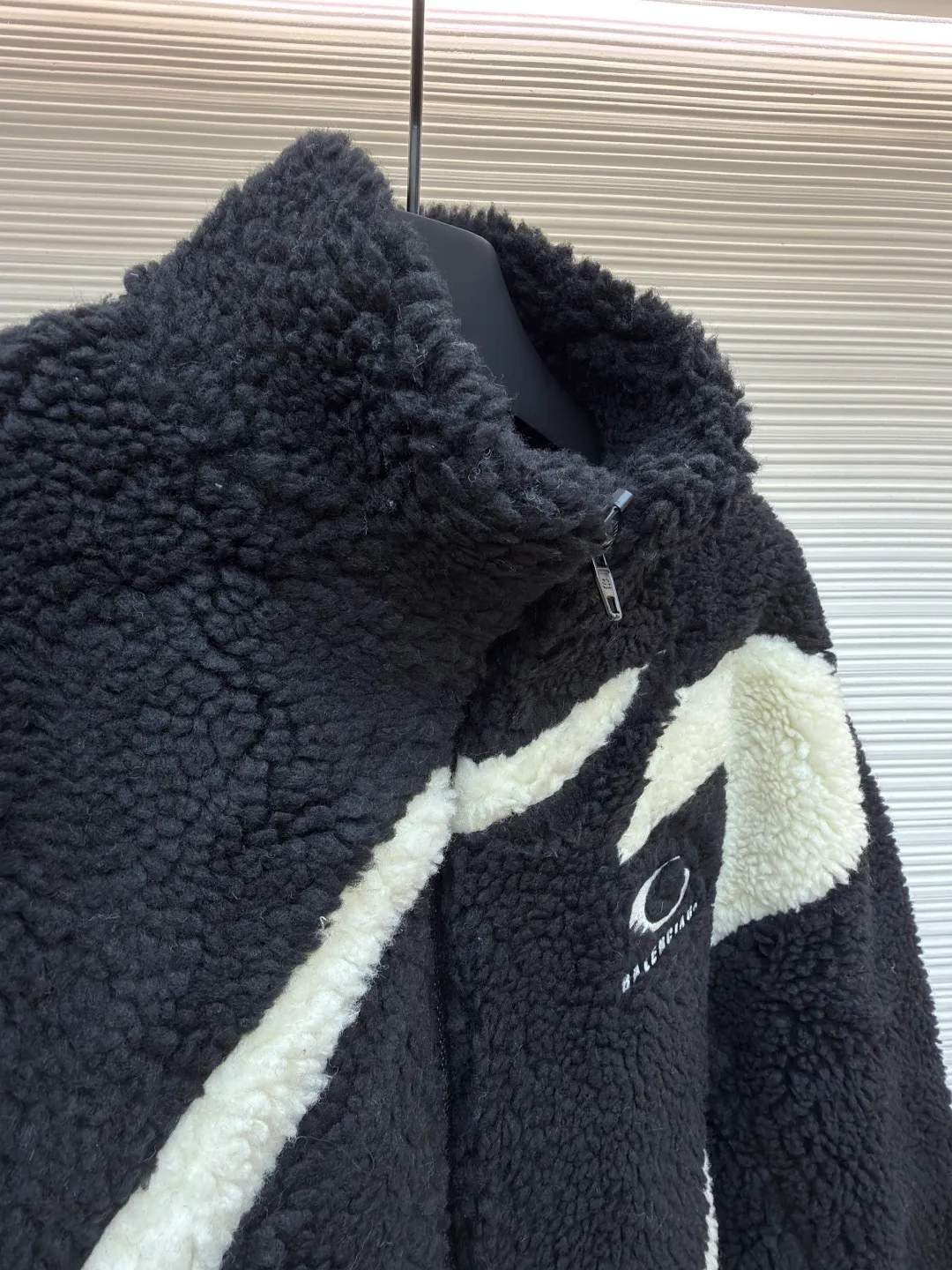 Balenciaga ski series sherpa stand collar jacket ●Original version: purchased and developed by 14616 ●Item number: 1681957-B50 ●Fabric: sherpa fabric ●Technology: made on positioning cutting machine ●Color: black and white ●Version: fitted version ●Weight: about 1190 grams ●Size: XXS-XS-S-M ●Description: Made of high-density imitation lamb wool fabric, the black/white two-color terry is pre-shrunk, making the velvet feel fluffy and not easy to shed. The core pattern of the body is a three-dimensional splicing process: the white terry pieces are precisely cut by laser, and the edges are sewn by hand stitching to form a smooth curve layer with the black base, and the error is controlled within 0.2cm. The chest logo uses a combination of flocking embossing and offset printing, and the brand words and patterns have both a three-dimensional feel and wear resistance. The placket is equipped with a hidden metal zipper, and the chain teeth are matte black-plated, making it smooth and visually low-key. The cuffs and hem are ribbed with the same fabric, and the elastic rebound rate is ≥90%. The inner lining is lined with light polyester fiber interlining to improve the comfort of putting on and taking off. The overall stitching is made of high-tenacity nylon thread. The even stitch length of 9 needles per centimeter takes into account both warmth retention and style. The overall wiring is straight and delicate, the fabric is comfortable and soft, and the color is consistent without color difference. It can be matched with the same style to create a fashionable look and control various occasions. Customized accessories, complete with three standards, same style for men and women!