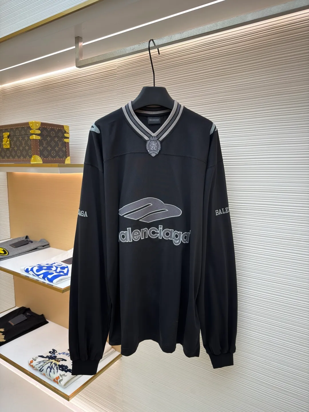 Balenciaga team series V-neck long sleeves ●Original version: purchased and developed by 8016 ●Item number: 1682073-A55 ●Fabric: plain knitted compact cotton fabric ●Technology: glue printing ●Color: black ●Version: loose version ●Weight: about 380 grams ●Size: XS-S-M-L ●Description: The main body is made of 24-count special woven compact cotton, with a weight of 185g/㎡. Compact spinning technology is applied in the spinning process, which significantly reduces yarn hairiness and makes the yarn smoother and stronger. This gives the fabric an unusually dense structure, a smooth and smooth surface, and excellent pilling resistance, while retaining the softness and breathability of pure cotton. The weight of 185g is light to middleweight, ensuring that the clothing is light, drapeable and can move freely. It is very suitable for creating a long-sleeved shirt that combines sportiness with daily comfort. The V-neck part is made of two different colors of high-elastic rib fabrics. The process step is to first weave ribbed belts of two colors separately, and then through precise cutting and splicing, form a V-shaped neckline with sharp color contrast. It breaks the monotony of the solid color body, uses strong color contrast to create a young and energetic visual focus, and optimizes the neck line. The pattern is pre-cut and formed into patches on fabrics of different materials or colors, and then covered on the body. Finally, high-density embroidery thread is used to fix the edges and outline the internal details. Its function is to create patterns with bright colors, strong texture contrast, three-dimensionality and durability. The edges of the pattern are strong and not easy to wear. A special elastic paste is screen-printed on the sleeves to create brightly colored patterns with a slightly coated feel. The elastic paste ensures that the printed area can stretch with the fabric without cracking. It forms a texture contrast between one flat and one convex with the three-dimensional sense of appliqué, which increases the interest and complexity of the design. The overall wiring is straight and delicate, the fabric is comfortable and soft, and the color is consistent without color difference. It can be matched with the same style to create a fashionable look and control various occasions. Customized accessories, complete with three standards, same style for men and women!