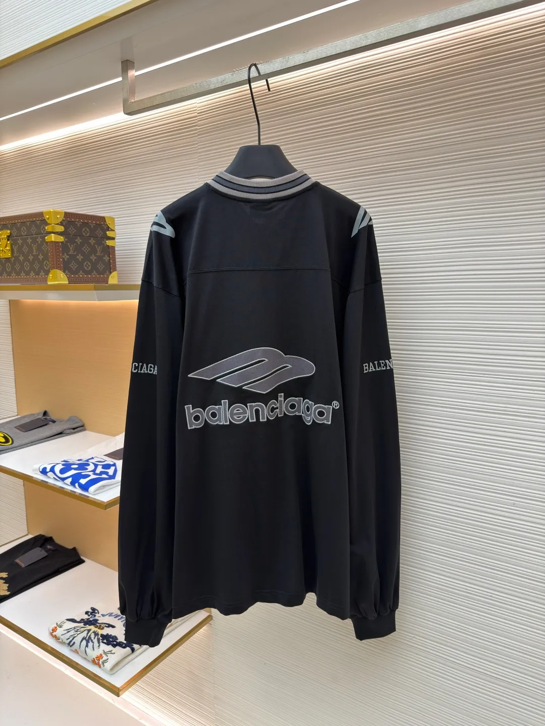 Balenciaga team series V-neck long sleeves ●Original version: purchased and developed by 8016 ●Item number: 1682073-A55 ●Fabric: plain knitted compact cotton fabric ●Technology: glue printing ●Color: black ●Version: loose version ●Weight: about 380 grams ●Size: XS-S-M-L ●Description: The main body is made of 24-count special woven compact cotton, with a weight of 185g/㎡. Compact spinning technology is applied in the spinning process, which significantly reduces yarn hairiness and makes the yarn smoother and stronger. This gives the fabric an unusually dense structure, a smooth and smooth surface, and excellent pilling resistance, while retaining the softness and breathability of pure cotton. The weight of 185g is light to middleweight, ensuring that the clothing is light, drapeable and can move freely. It is very suitable for creating a long-sleeved shirt that combines sportiness with daily comfort. The V-neck part is made of two different colors of high-elastic rib fabrics. The process step is to first weave ribbed belts of two colors separately, and then through precise cutting and splicing, form a V-shaped neckline with sharp color contrast. It breaks the monotony of the solid color body, uses strong color contrast to create a young and energetic visual focus, and optimizes the neck line. The pattern is pre-cut and formed into patches on fabrics of different materials or colors, and then covered on the body. Finally, high-density embroidery thread is used to fix the edges and outline the internal details. Its function is to create patterns with bright colors, strong texture contrast, three-dimensionality and durability. The edges of the pattern are strong and not easy to wear. A special elastic paste is screen-printed on the sleeves to create brightly colored patterns with a slightly coated feel. The elastic paste ensures that the printed area can stretch with the fabric without cracking. It forms a texture contrast between one flat and one convex with the three-dimensional sense of appliqué, which increases the interest and complexity of the design. The overall wiring is straight and delicate, the fabric is comfortable and soft, and the color is consistent without color difference. It can be matched with the same style to create a fashionable look and control various occasions. Customized accessories, complete with three standards, same style for men and women!