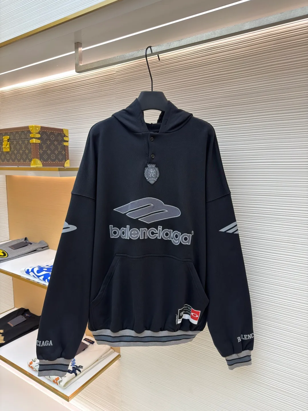 Balenciaga 3B football Polo hoodie ●Original version: Purchased and developed for 9999 ●Item number: 1681997-B40 ●Fabric: cotton fabric ●Technology: embroidery applique production ●Color: black ●Version: loose fit ●Weight: about 860 grams ●Size: XS-S-M-L ●Description: The neckline adopts a half-open button design and is decorated with metal badges to enhance the layered look; the main body of the garment presents the brand logo through three-dimensional foam printing technology, and the grayscale gradient effect enhances the visual texture. The cuffs and hem are edged with contrasting ribbing, which has moderate elasticity and is not easily deformed; a collage label is embedded in the left hem, and the details echo the brand's street style. The partial logo embroidery on the shoulders and cuffs echoes the main pattern. The overall craftsmanship takes into account practical wearability and brand recognition, making it suitable for daily casual or trendy looks. The overall wiring is straight and delicate, the fabric is comfortable and soft, and the color is consistent without color difference. It can be matched with the same style to create a fashionable look and control various occasions. Customized accessories, complete with three standards, same style for men and women!