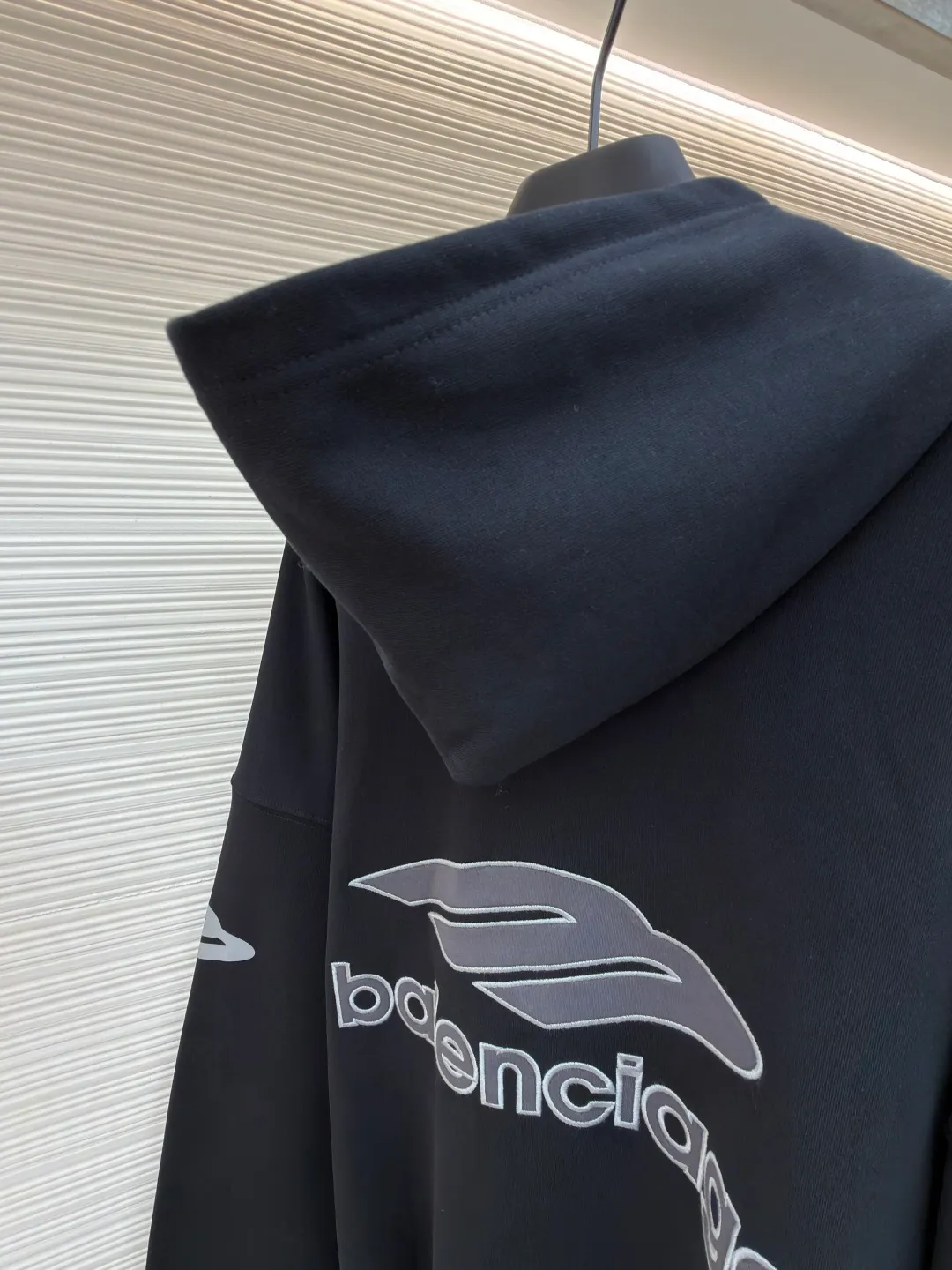 Balenciaga 3B football Polo hoodie ●Original version: Purchased and developed for 9999 ●Item number: 1681997-B40 ●Fabric: cotton fabric ●Technology: embroidery applique production ●Color: black ●Version: loose fit ●Weight: about 860 grams ●Size: XS-S-M-L ●Description: The neckline adopts a half-open button design and is decorated with metal badges to enhance the layered look; the main body of the garment presents the brand logo through three-dimensional foam printing technology, and the grayscale gradient effect enhances the visual texture. The cuffs and hem are edged with contrasting ribbing, which has moderate elasticity and is not easily deformed; a collage label is embedded in the left hem, and the details echo the brand's street style. The partial logo embroidery on the shoulders and cuffs echoes the main pattern. The overall craftsmanship takes into account practical wearability and brand recognition, making it suitable for daily casual or trendy looks. The overall wiring is straight and delicate, the fabric is comfortable and soft, and the color is consistent without color difference. It can be matched with the same style to create a fashionable look and control various occasions. Customized accessories, complete with three standards, same style for men and women!