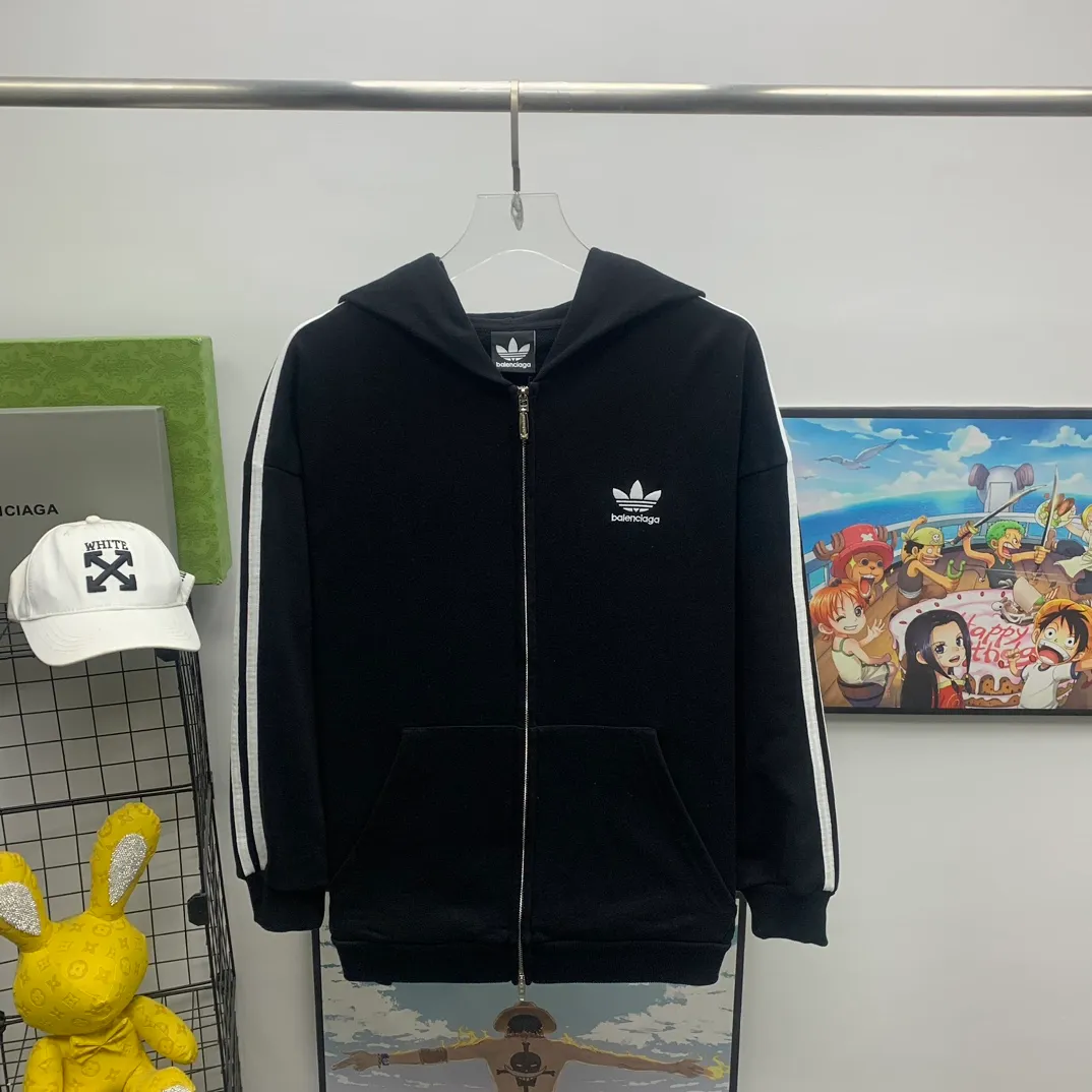 The top tested version of BALENCIAGA/Paris co-branded Adidas three-leaf clover LOGO embroidered hooded sweatshirt. The fabric is made of Paris ZP custom-woven and dyed cotton terry fabric. Weighing 450 grams, the cloth surface is clean. The cloth pattern is clear, soft and comfortable. The threads are dyed with no color difference. The classic pattern embroidery uses imported embroidery, and the letters are clear, three-dimensional and without rough edges. Custom-woven two-way zipper hardware, the upper zipper is BALENCIAGA, the lower zipper is Adidas, with electroplating effect! The sense of high-end is straight away! Comparisons welcome. The version adopts OS loose shoulder design. Same style for men and women. Color: Black Size: XS-L P:410