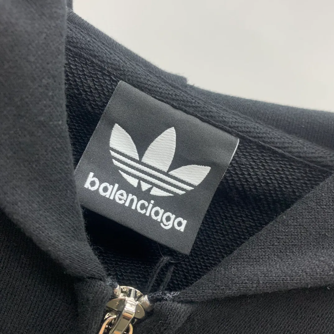 The top tested version of BALENCIAGA/Paris co-branded Adidas three-leaf clover LOGO embroidered hooded sweatshirt. The fabric is made of Paris ZP custom-woven and dyed cotton terry fabric. Weighing 450 grams, the cloth surface is clean. The cloth pattern is clear, soft and comfortable. The threads are dyed with no color difference. The classic pattern embroidery uses imported embroidery, and the letters are clear, three-dimensional and without rough edges. Custom-woven two-way zipper hardware, the upper zipper is BALENCIAGA, the lower zipper is Adidas, with electroplating effect! The sense of high-end is straight away! Comparisons welcome. The version adopts OS loose shoulder design. Same style for men and women. Color: Black Size: XS-L P:410