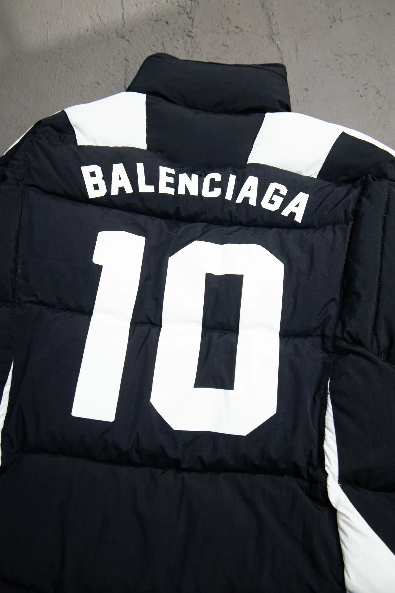 💰760 [Highest version, differentiated currency] Balenciaga / Balenciaga Blcg 24SS Manchester United football No. 10 black and white stitching joint stitching training down jacket, official website synchronized. The surface fabric and lining are made of customized high-density cloud-feel nylon fabric. The fabric has a level 4 water-repellent coating process. The lining is made of double-layer 330 gallbladder. Filled with 600 grams of Xinjiang pearl particle cotton. Extremely full!  The fabrics are the same as the original. Double-layer materials are used. The whole dress is full of style. Professional pattern makers from the original big-name OEM factory make patterns. Laser three-dimensional cutting. Because there are many splicing places, ordinary pattern makers are difficult to handle. Good products are made with care. Good goods take a long time. The whole body embroidery is operated by professional embroidery machines imported from island countries to make the embroidery details reach the top level. The whole body printing parts are operated using imported environmentally friendly offset printing technology. The printing is firm. The whole clothing accessories are molded and customized with hardware zippers and air holes. Double-hole limit buckle All have the same LOGO as the original version. Customized and washed as the original version. Main mark. Brand zipper seal bag. Brand LOGO moisture-proof paper. 3D laser cutting. Double-layer material. 5 meters of cloth for the whole piece. Extremely high cost. Composed of 47 pieces. Very slow production. Zipper pockets on both sides. Elastic cuff design. Imported environmentally friendly glue thermoset ink printing technology. Tajima high-speed embroidery machine embroidery Sporty B. Three-dimensional and full. The cuffs are equipped with new custom football embroidery patches. Customized hardware zippers. Double slider design. Customized original air holes. Customized original logo double-hole limit buckles. Original main mark and washed tag. Brand packaging. Color: black. Size: 46/48/50/52.