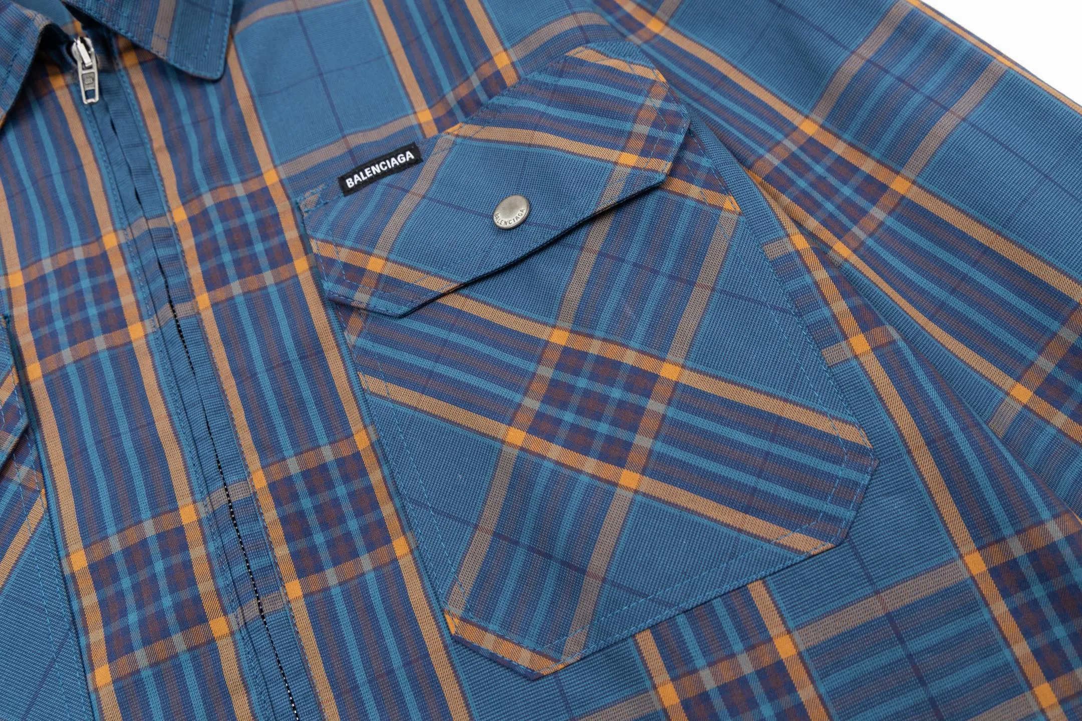 🅿️810 BLCG 25SS Blue Style Zippered Shirt Combining the delicate feel of jacquard fabric, the heavy feel of the double-layer structure and the functional feel of the zipper snap button, this item cleverly blurs the boundaries between shirts, jackets and lightweight coats. It not only retains the shape of a shirt, but also has the practical attributes of a jacket, making it very suitable as an outer layer in spring and autumn or as an inner layer in winter. Using double-layer composite jacquard technology, functional cotton yarns are three-dimensionally woven through an electronic jacquard machine. The plaid pattern is formed at once through the precise interweaving of warp and weft yarns during the weaving process, forming a permanent three-dimensional texture. The double-layer structure not only gives the fabric excellent stiffness and warmth retention properties, but also achieves temperature regulation through the air layer principle. Innovatively adopts the composite design of box-style straight cut and full zipper placket system. The straight hem provides a modern silhouette and ample layering space, while precision zippers replace traditional buttons, which not only enhances wind resistance but also creates smooth visual lines. The shoulders and armholes are three-dimensionally cut to ensure optimal freedom of movement despite the loose silhouette. The chest logo uses a jacquard letter logo to ensure the unity of decoration and function; the engraved four-button system is distributed on the cuffs, pockets and other locations to provide a precise closing experience; all seam interfaces have been strengthened to significantly enhance the durability and professional quality of the item. Size:XS-S-M-L