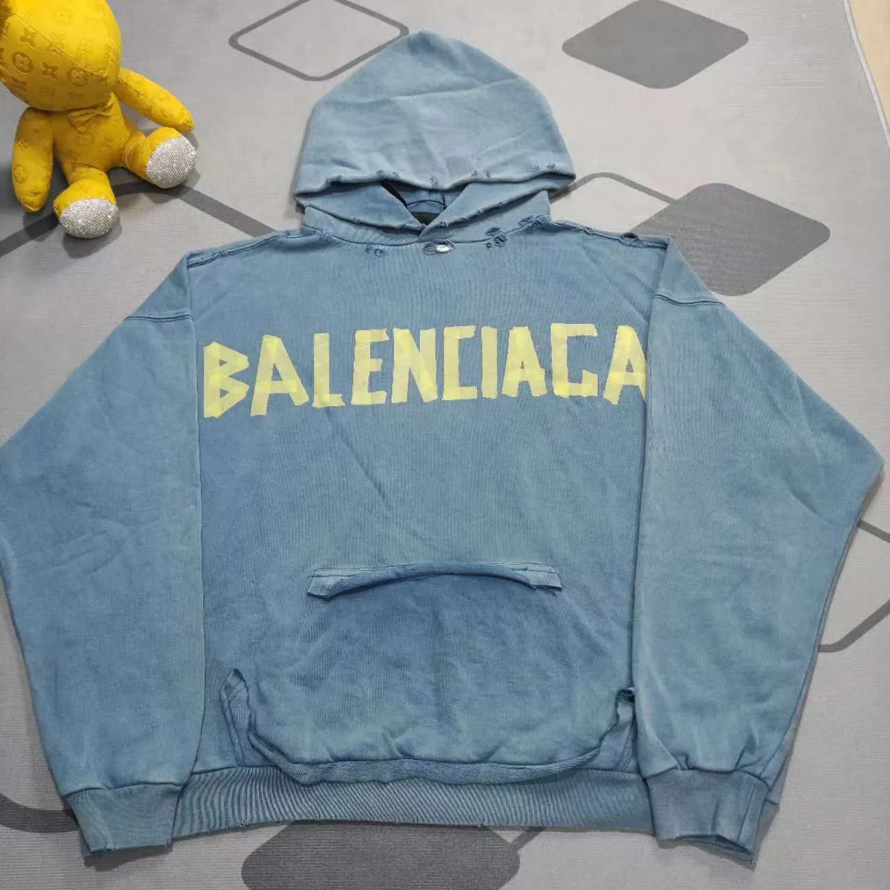 The top proven version of Balenciaga 23SS haze blue masking paper printed letters double-sided logo hooded loose hooded sweatshirt. This hoodie has a very interesting and cute design. The kangaroo pocket on the front of the large body is a reverse-cut design. The double side pockets are hollowed out, which actually deceives your vision when viewed from the front. The real pockets are sewn on the terry bottom on the reverse side. It is time-consuming and labor-intensive, but it is the core theme of the entire hoodie that cannot be ignored. In the same detail, the double side pockets are hemmed and stitched. And processed with holes; 480g heavy-weight pure cotton fabric with fine small terry bottom. After heavy mud dyeing and washing, the fabric still has a thick foundation and is comfortable and soft. The front and back double-sided textured paper transfer LOGO, and the front and back printing colors are different. The loose and large drop shoulder design is unisex. This style is also very suitable for girls to match. It is easy to create a lazy and casual street feel of the United States and France. Many holes are processed by hand grinding wheels on the body. Traces of muddying can be seen on the neckline, shoulder line, and side cuff splicing, but the visual effect transition is natural and soft without any sense of dirt. The old effect of the entire hoodie is excellent. The cuff threads are custom-woven in color; the packaging is washed and customized. The new gray silver letter main logo. The dropped shoulder model does not include shoulder width. The version is Kanye’s American style. Short and wide street casual version. From short sleeves to sweaters, this style is definitely not to be missed. Color: mud-dyed custom-woven navy Size: XS-S-M (Can be worn by both men and women, OS is loose and dropped on the shoulders) P:510
