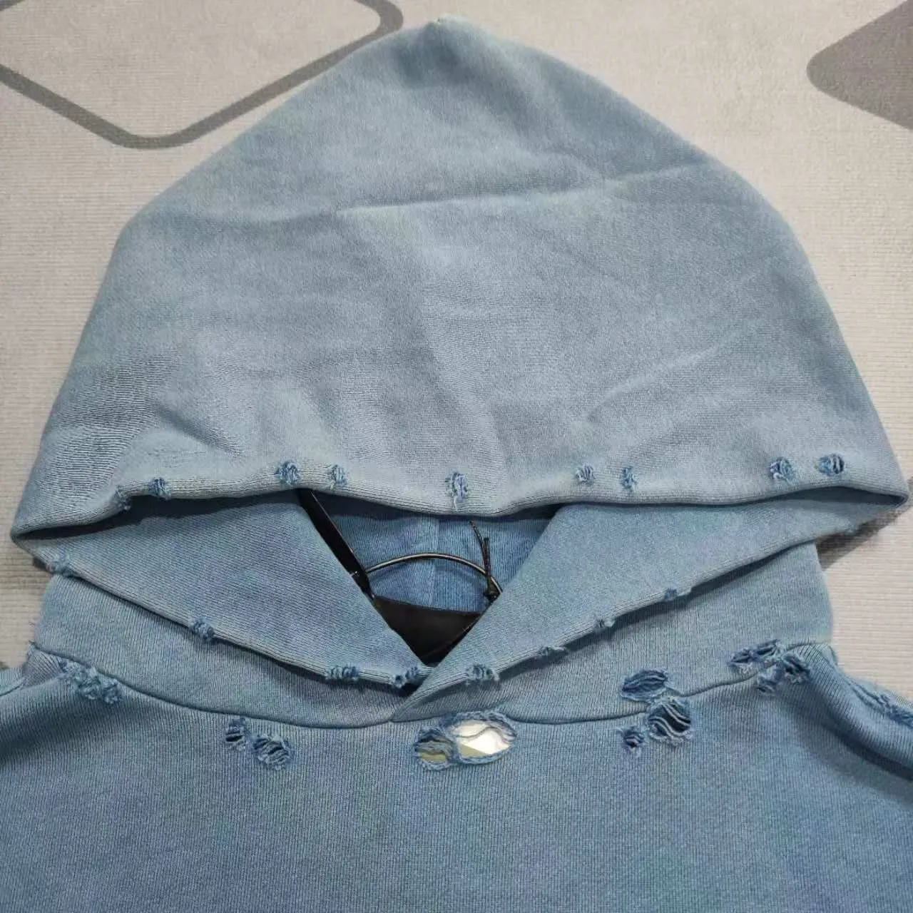 The top proven version of Balenciaga 23SS haze blue masking paper printed letters double-sided logo hooded loose hooded sweatshirt. This hoodie has a very interesting and cute design. The kangaroo pocket on the front of the large body is a reverse-cut design. The double side pockets are hollowed out, which actually deceives your vision when viewed from the front. The real pockets are sewn on the terry bottom on the reverse side. It is time-consuming and labor-intensive, but it is the core theme of the entire hoodie that cannot be ignored. In the same detail, the double side pockets are hemmed and stitched. And processed with holes; 480g heavy-weight pure cotton fabric with fine small terry bottom. After heavy mud dyeing and washing, the fabric still has a thick foundation and is comfortable and soft. The front and back double-sided textured paper transfer LOGO, and the front and back printing colors are different. The loose and large drop shoulder design is unisex. This style is also very suitable for girls to match. It is easy to create a lazy and casual street feel of the United States and France. Many holes are processed by hand grinding wheels on the body. Traces of muddying can be seen on the neckline, shoulder line, and side cuff splicing, but the visual effect transition is natural and soft without any sense of dirt. The old effect of the entire hoodie is excellent. The cuff threads are custom-woven in color; the packaging is washed and customized. The new gray silver letter main logo. The dropped shoulder model does not include shoulder width. The version is Kanye’s American style. Short and wide street casual version. From short sleeves to sweaters, this style is definitely not to be missed. Color: mud-dyed custom-woven navy Size: XS-S-M (Can be worn by both men and women, OS is loose and dropped on the shoulders) P:510